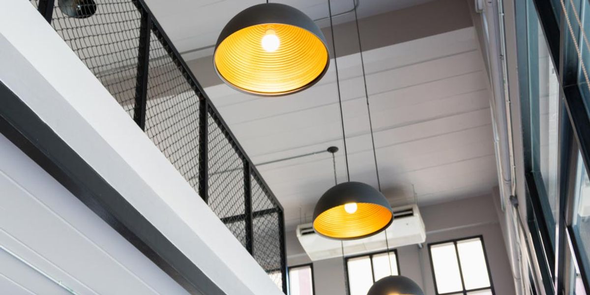 Black dome pendant lights hanging in a double-height stairwell