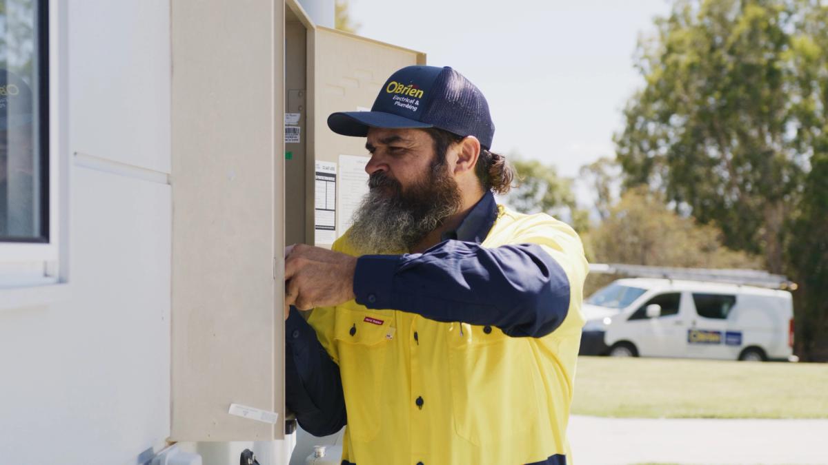 An O’Brien electrician opening an outdoor meter box at the side of a house