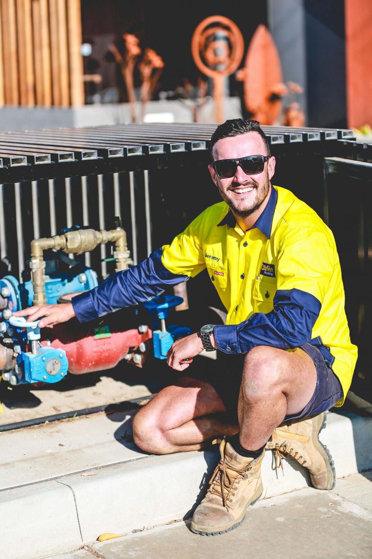 An O’Brien plumber crouched beside a backflow prevention assembly