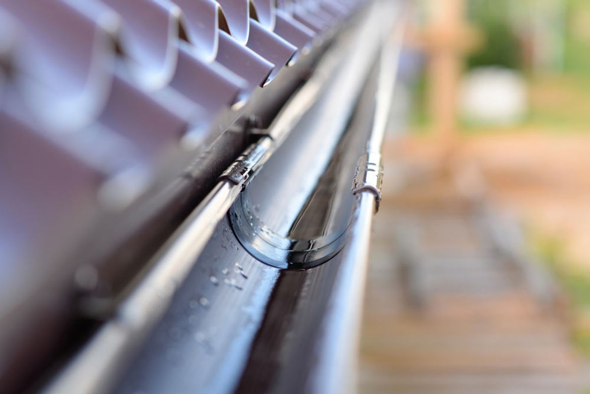 Close-up of guttering and a bracket along the edge of a metal roof