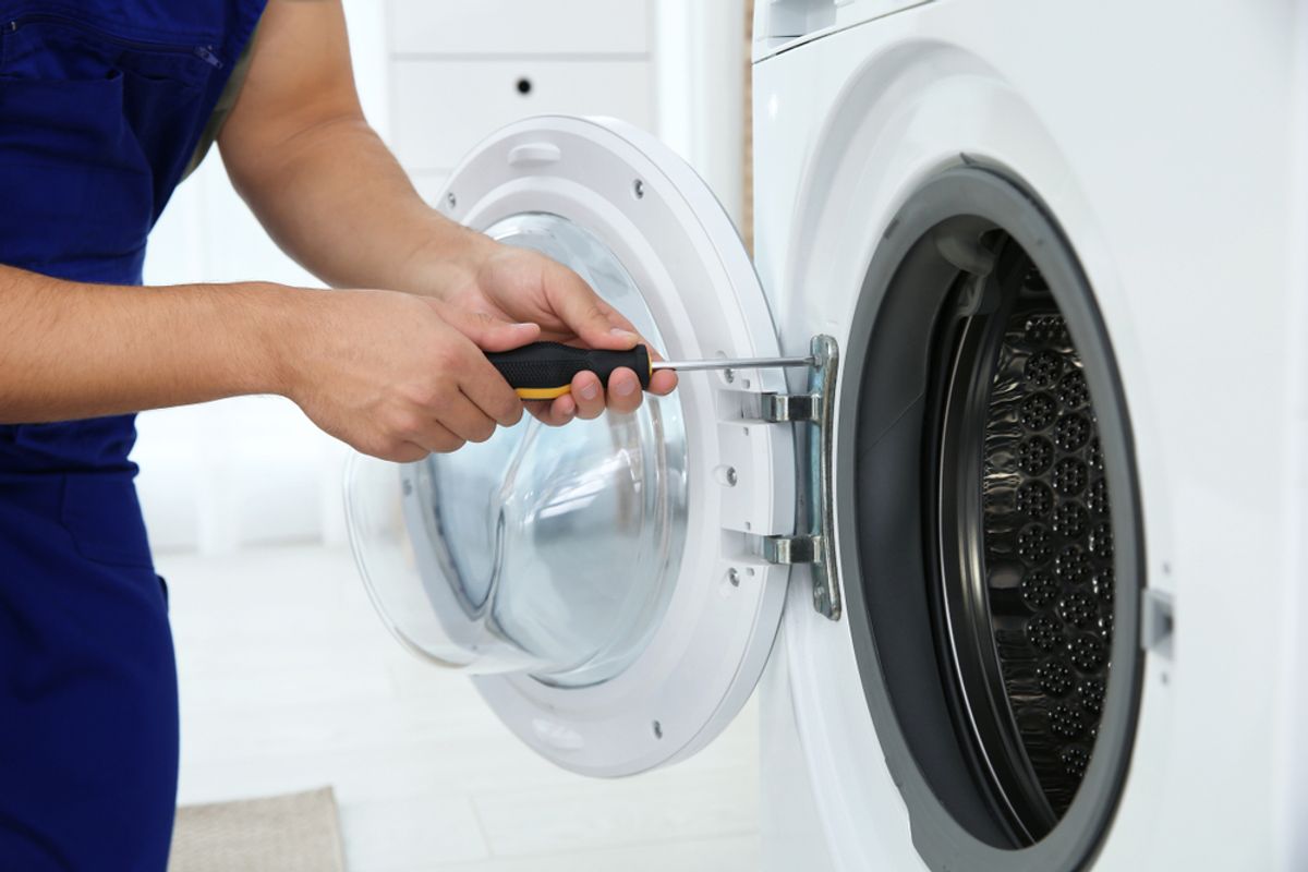 Hands repairing the door of a front-loading washing machine
