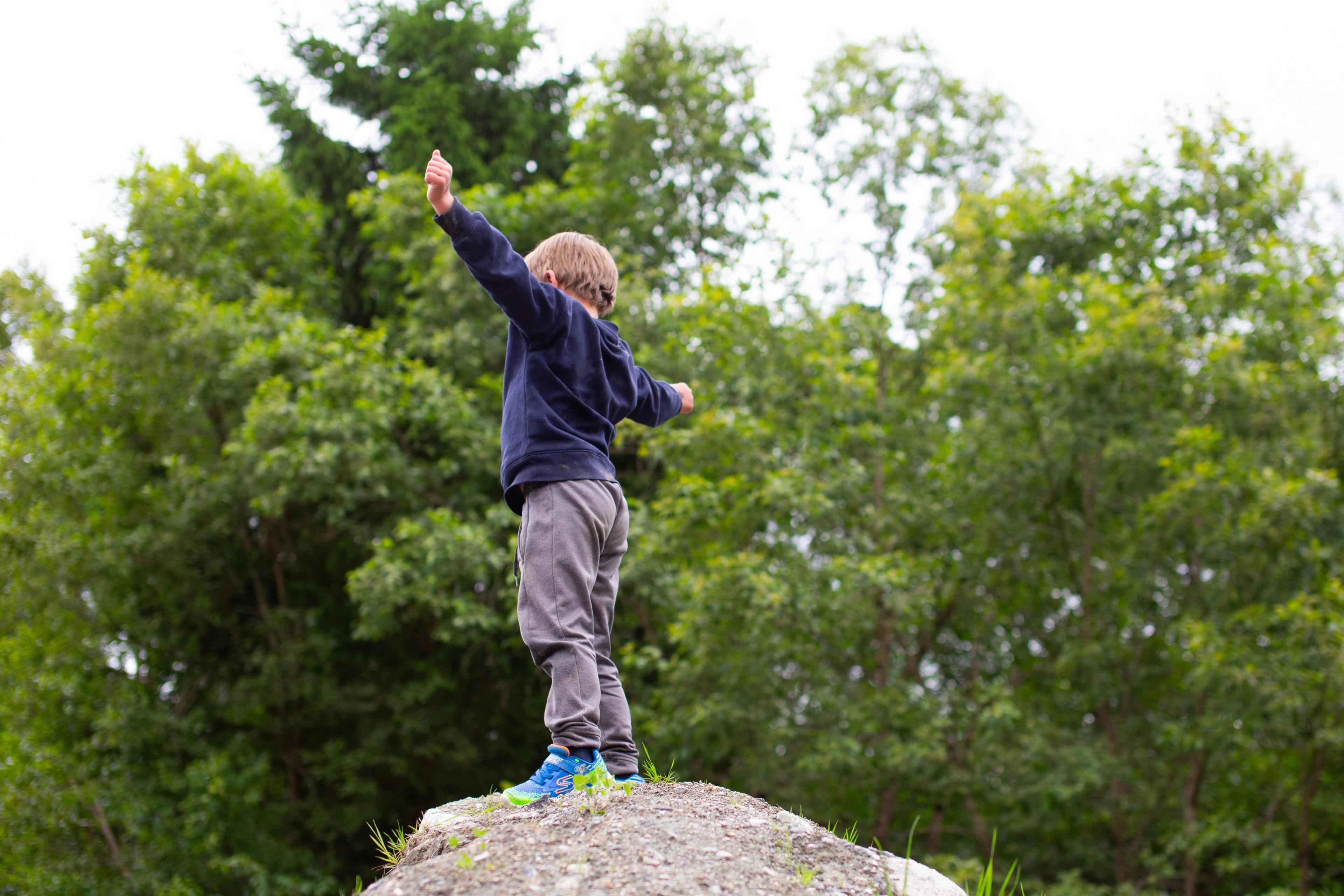 Barn på toppen av haugen med armene i været.