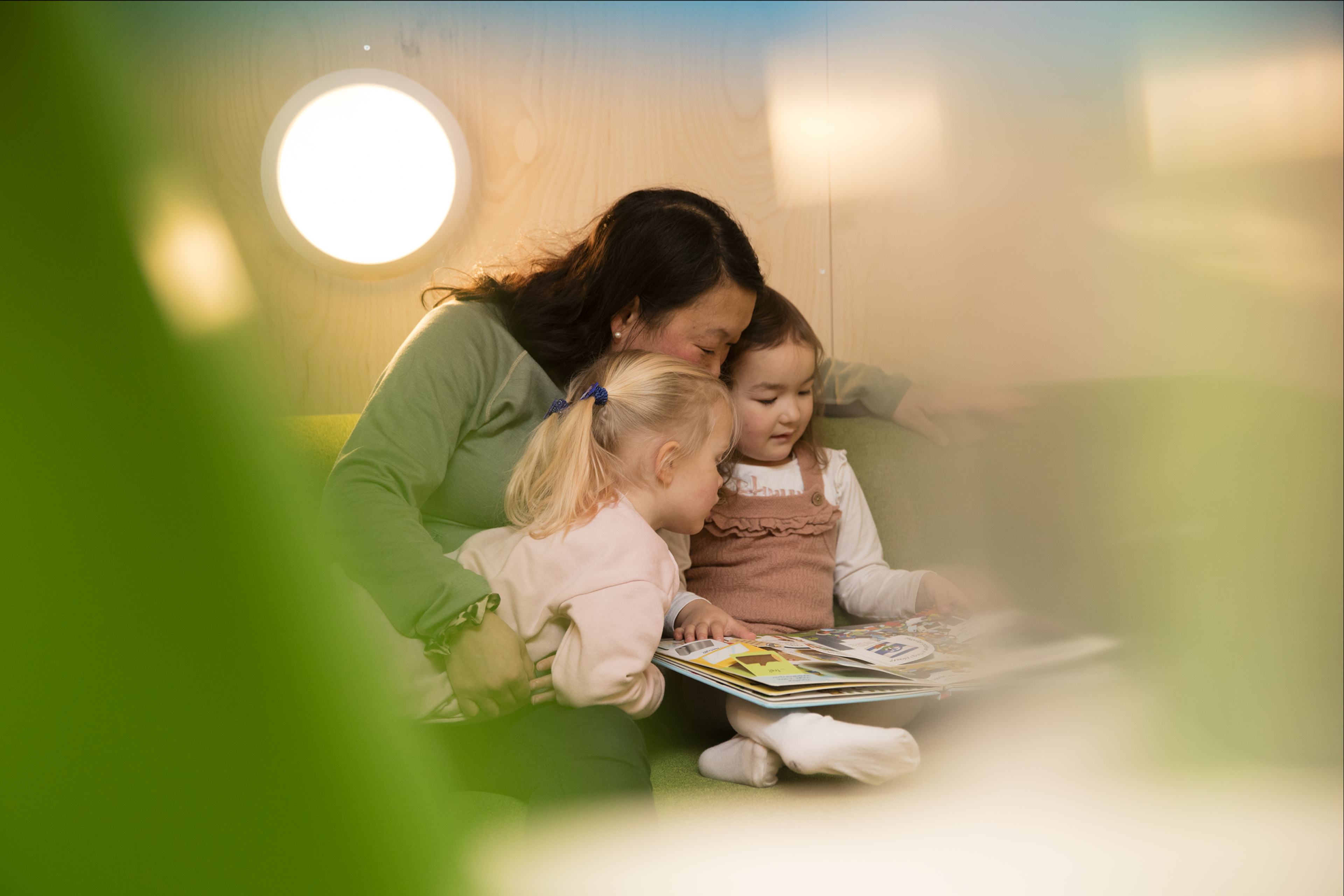 a woman reads a book to two little girls