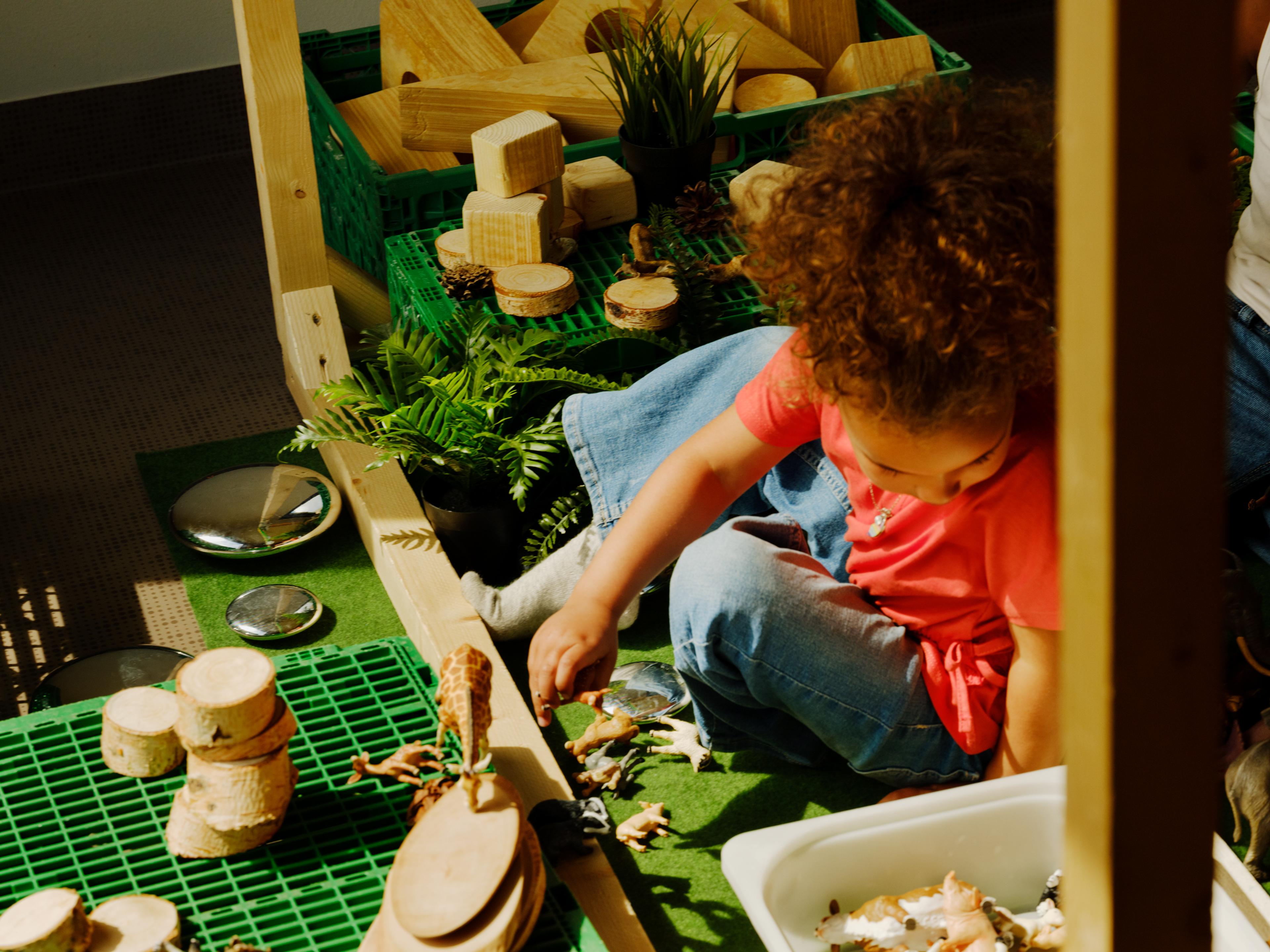 a little girl is sitting on the floor playing with wooden blocks .