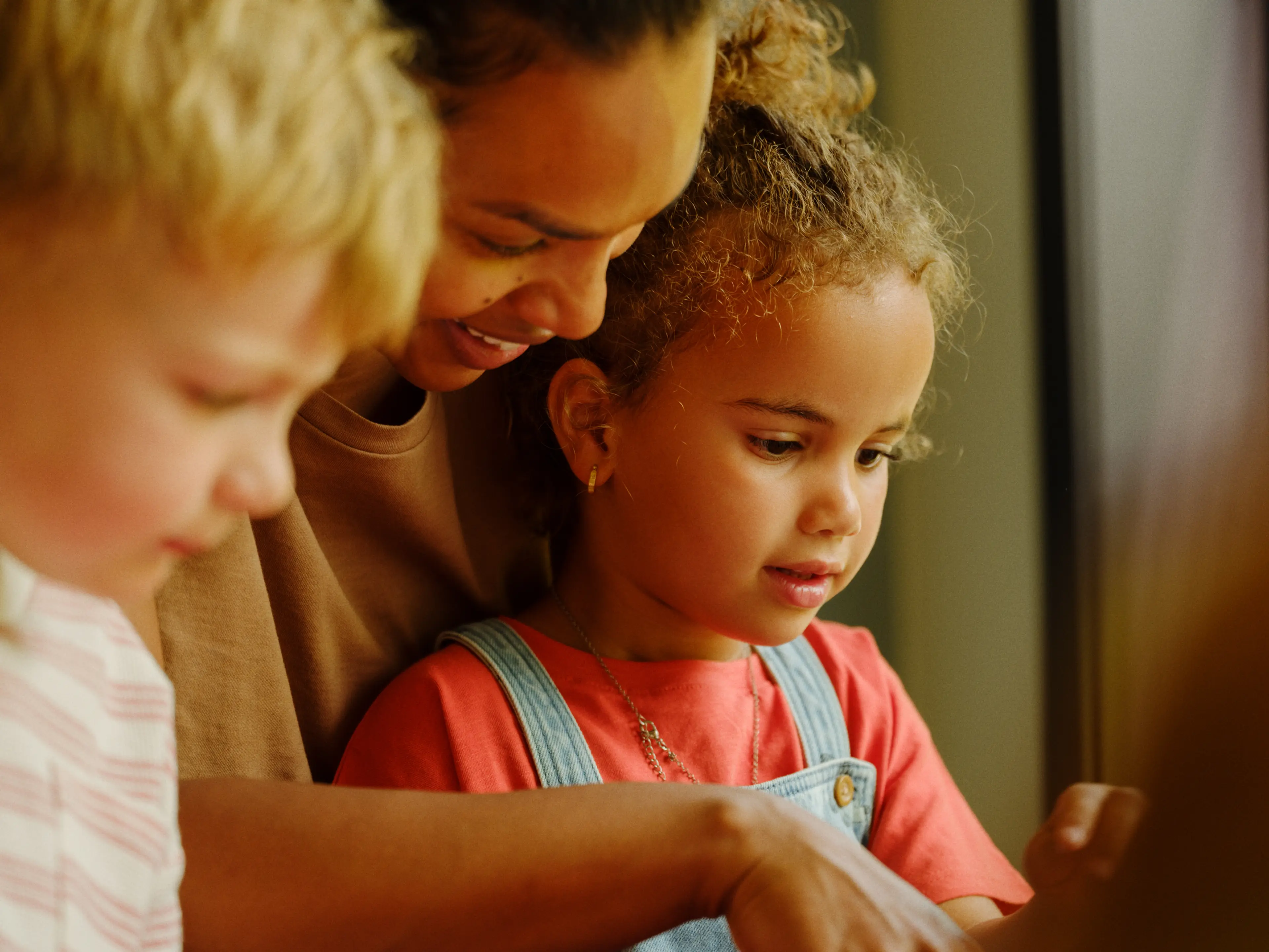 a woman and two children are looking at a tablet