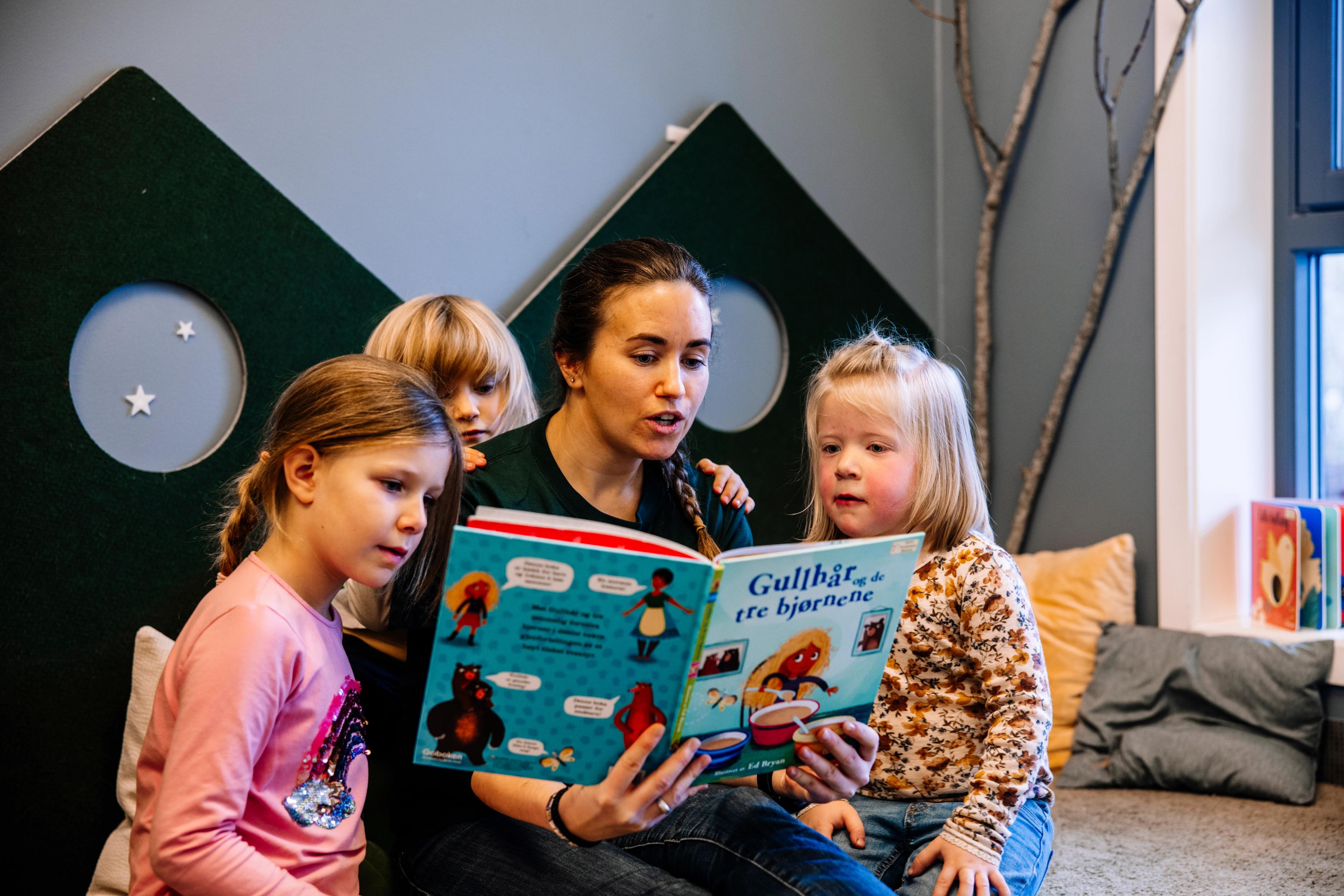 Voksen som leser bok sammen med barn - Espira barnehage