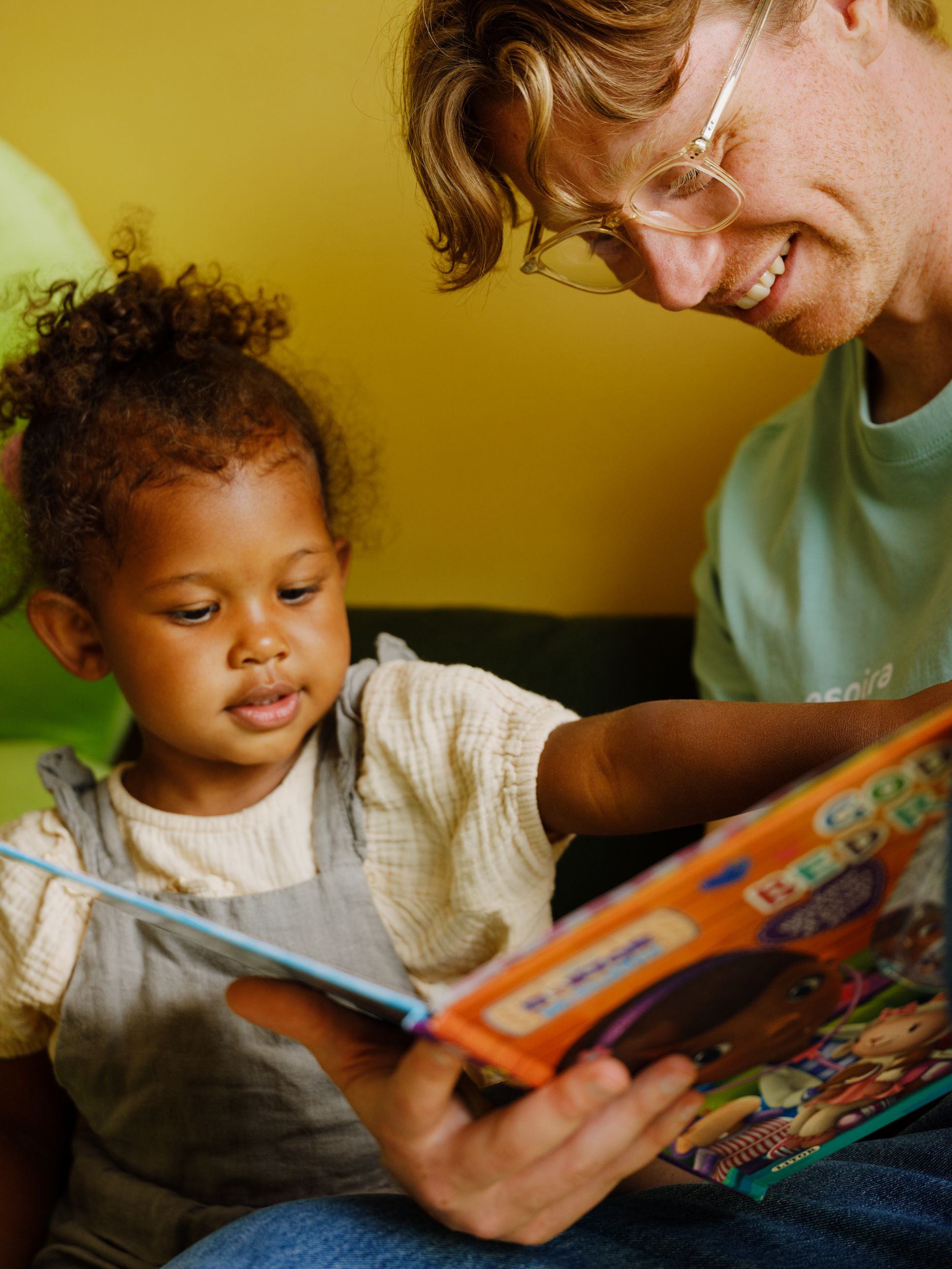 a man is reading a book to a little girl .