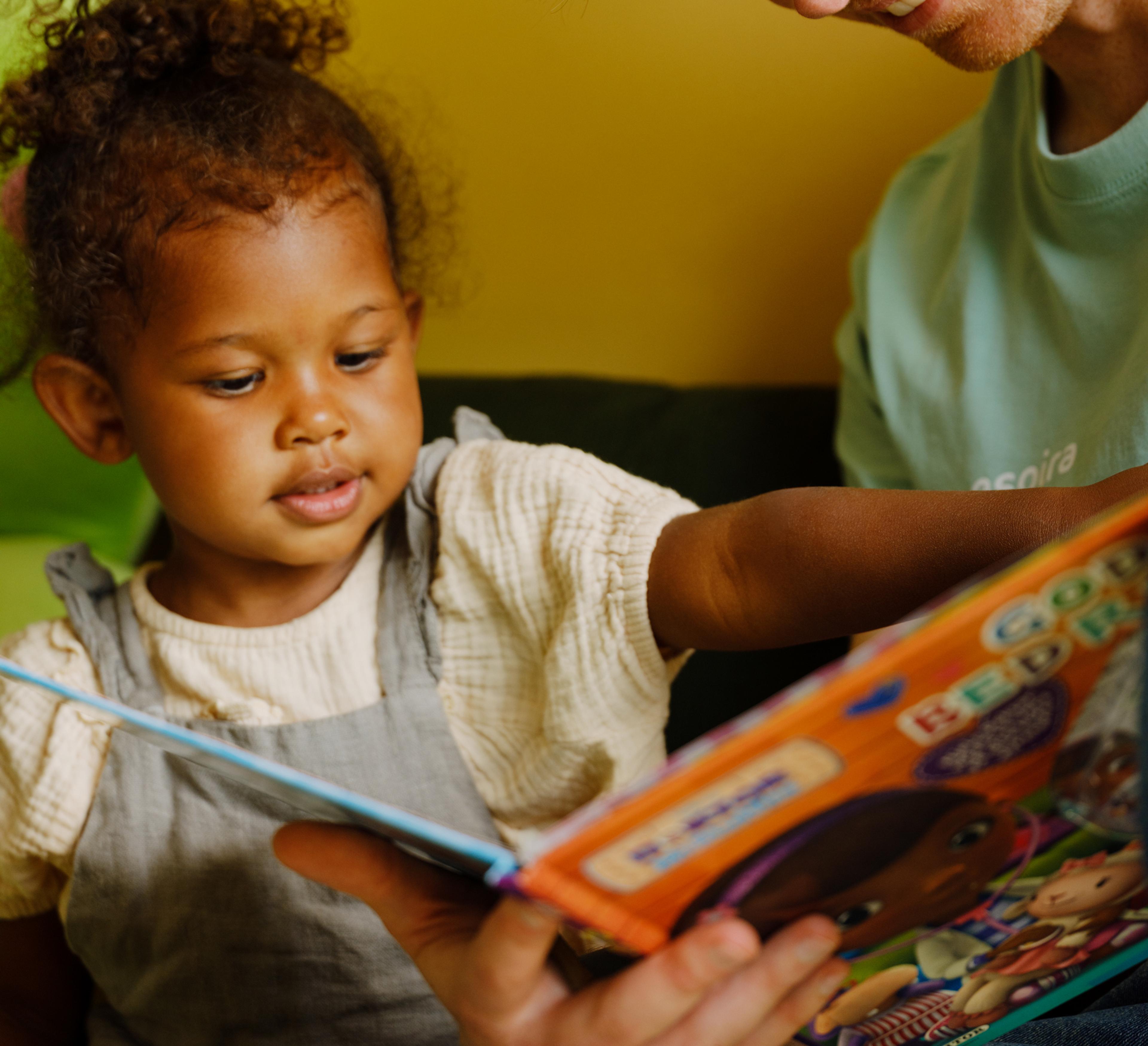 a man is reading a book to a little girl .
