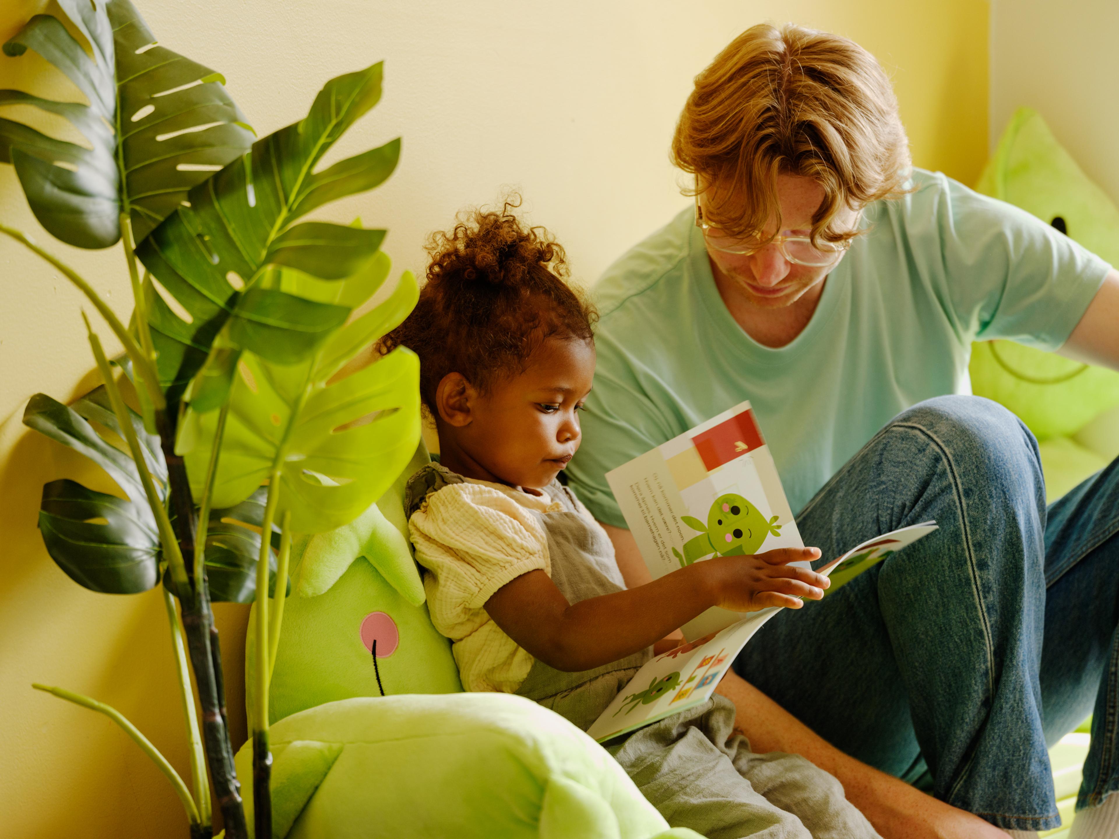 a woman is reading a book to a little girl .