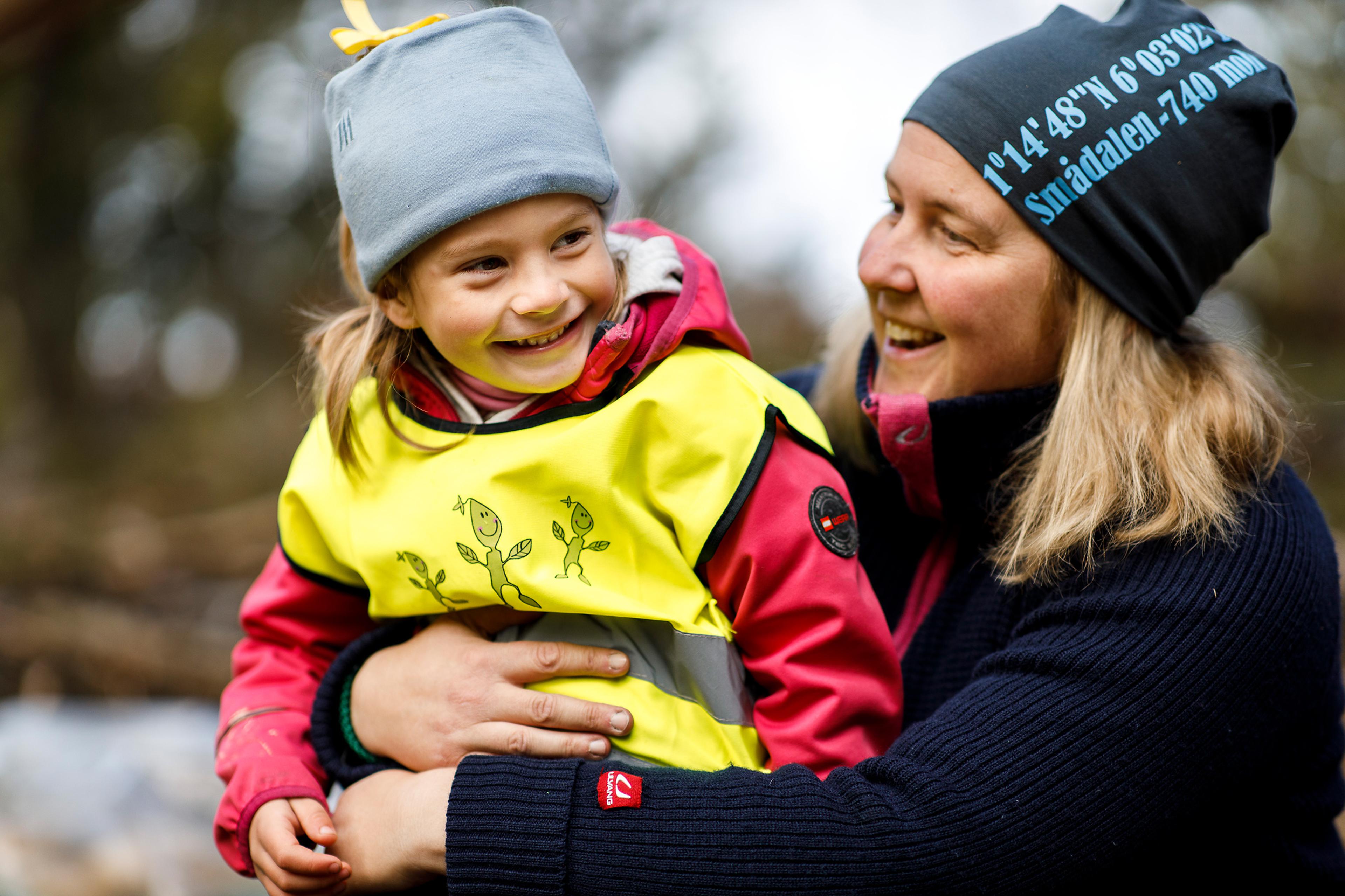 a woman is holding a little girl in her arms .