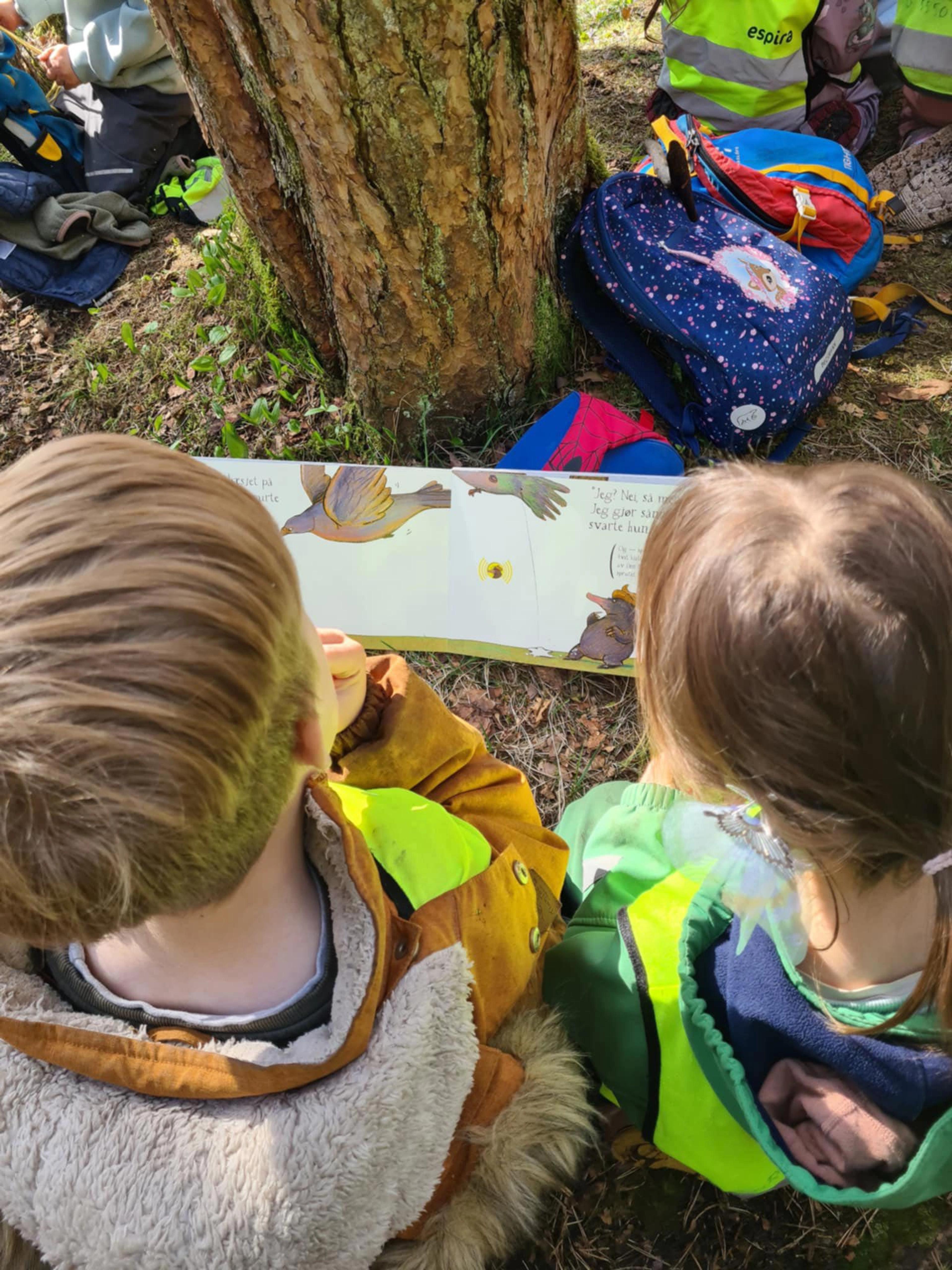Barn i Espira Eventyrskogen som leser bok ute