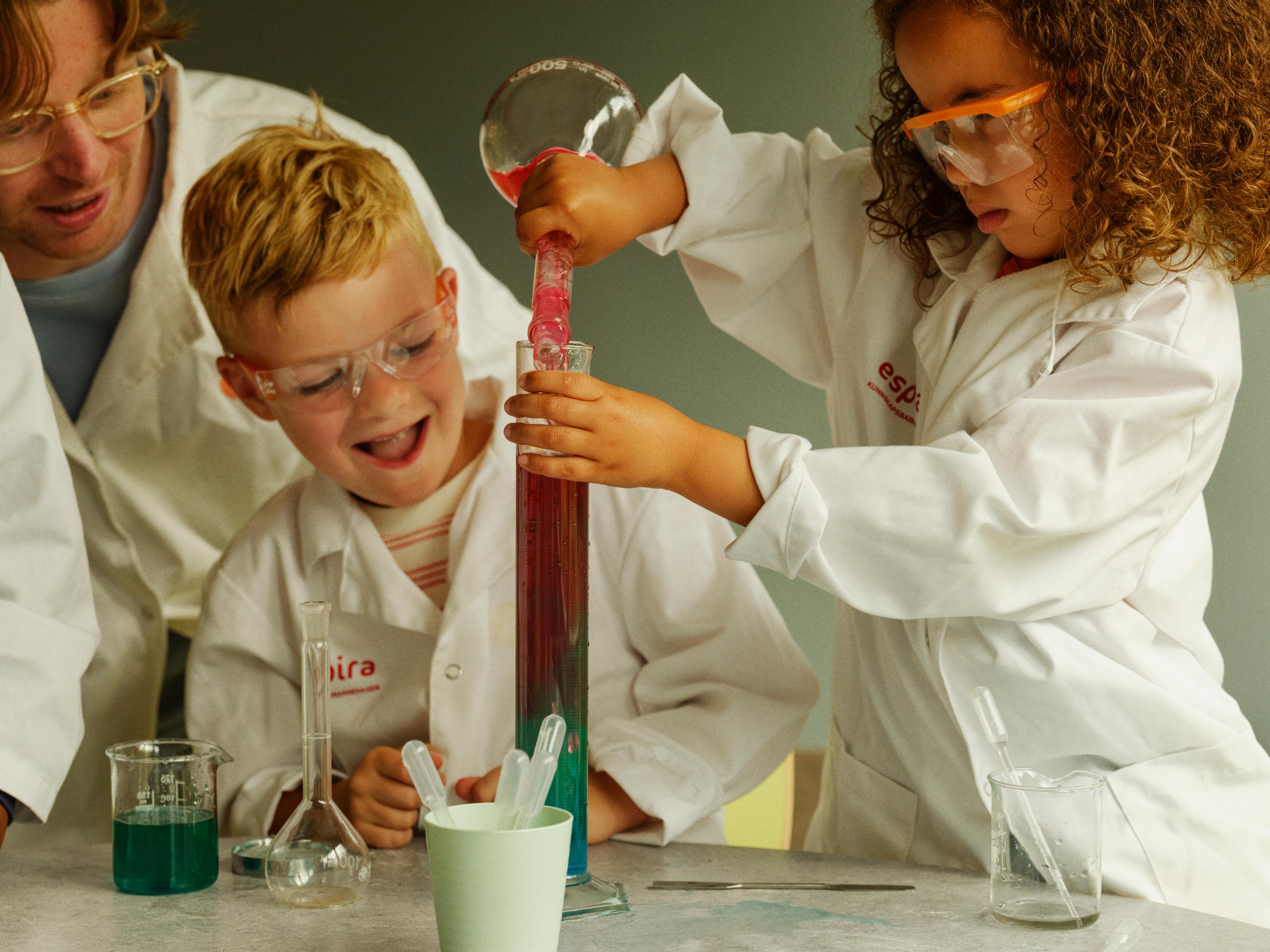 a group of children are doing a science experiment in a lab .