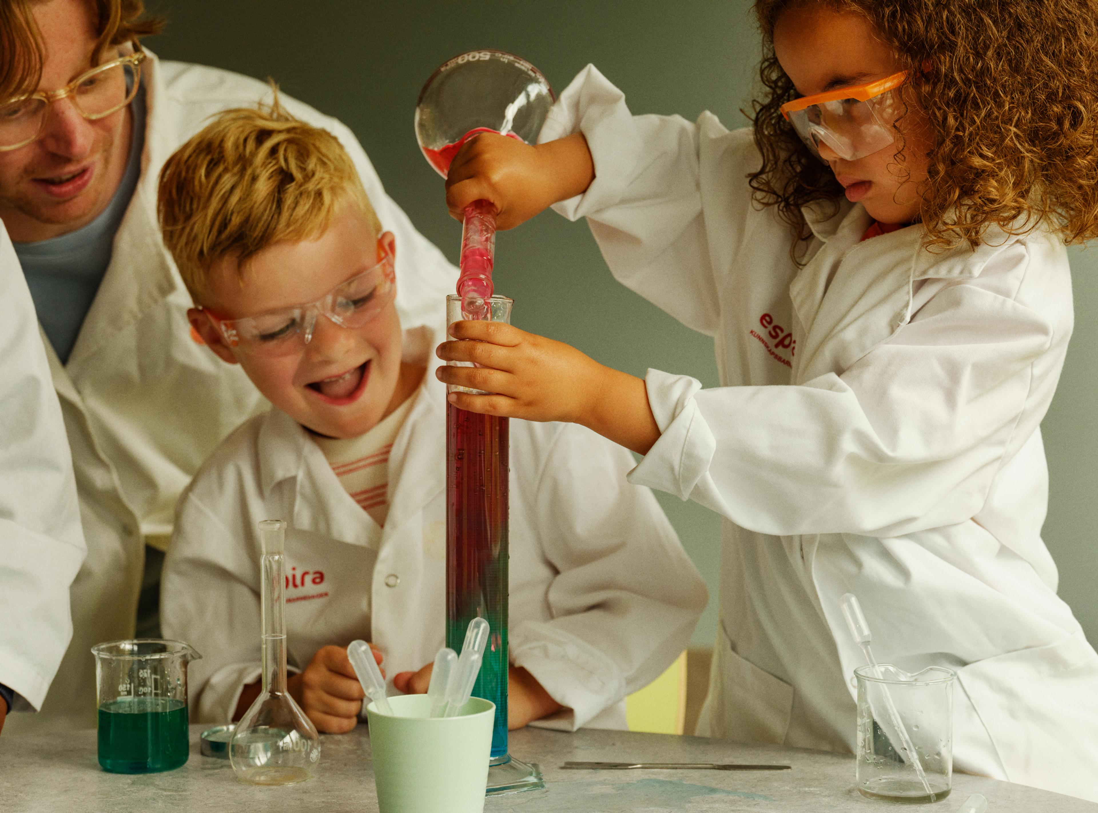 a group of children are doing a science experiment in a lab .