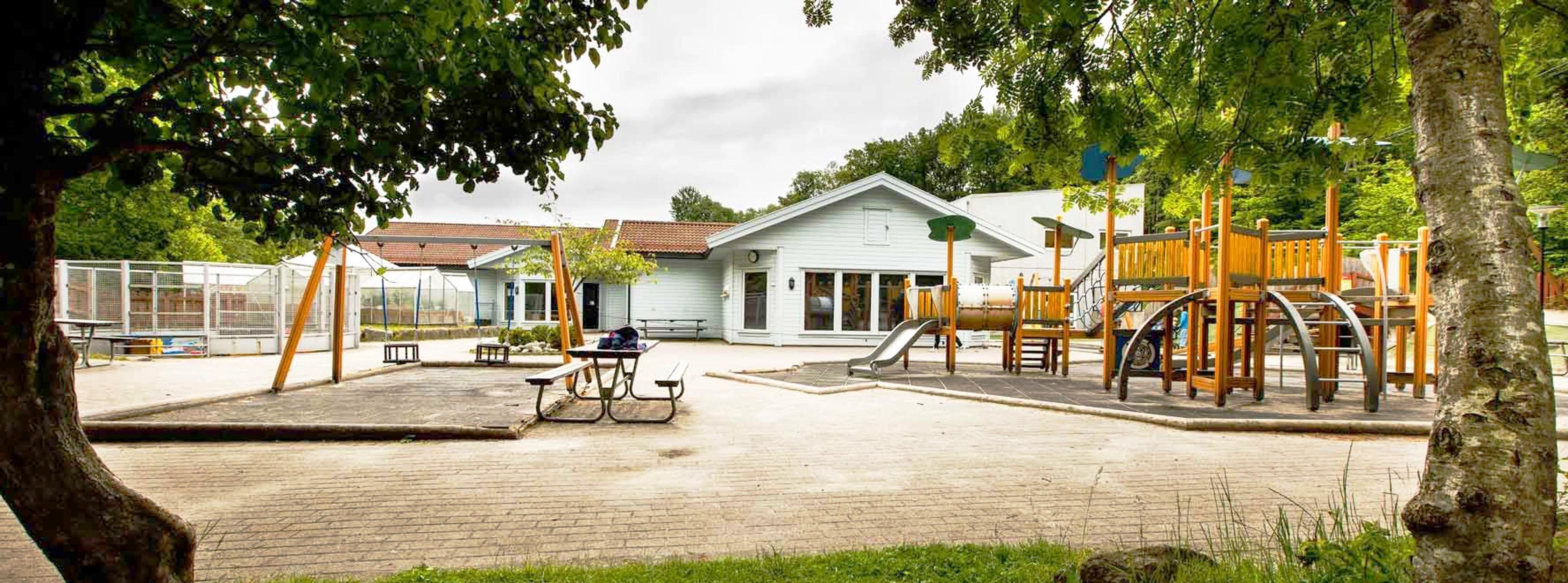 Fasade på Espira Sånum barnehage med lekeapparater i uteområdet