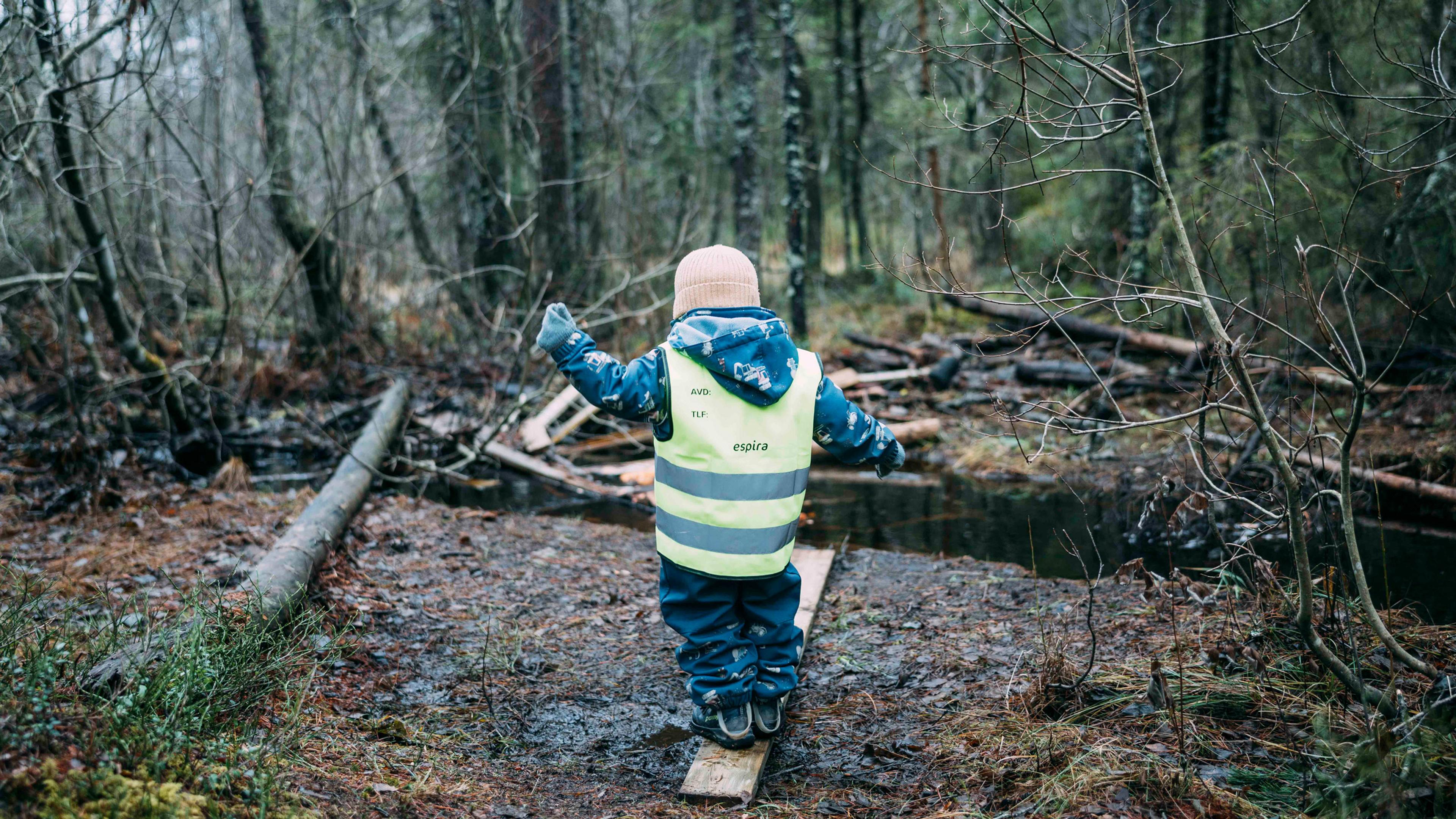 Barn i refleksvest som øver motorikk ved å balansere på en planke