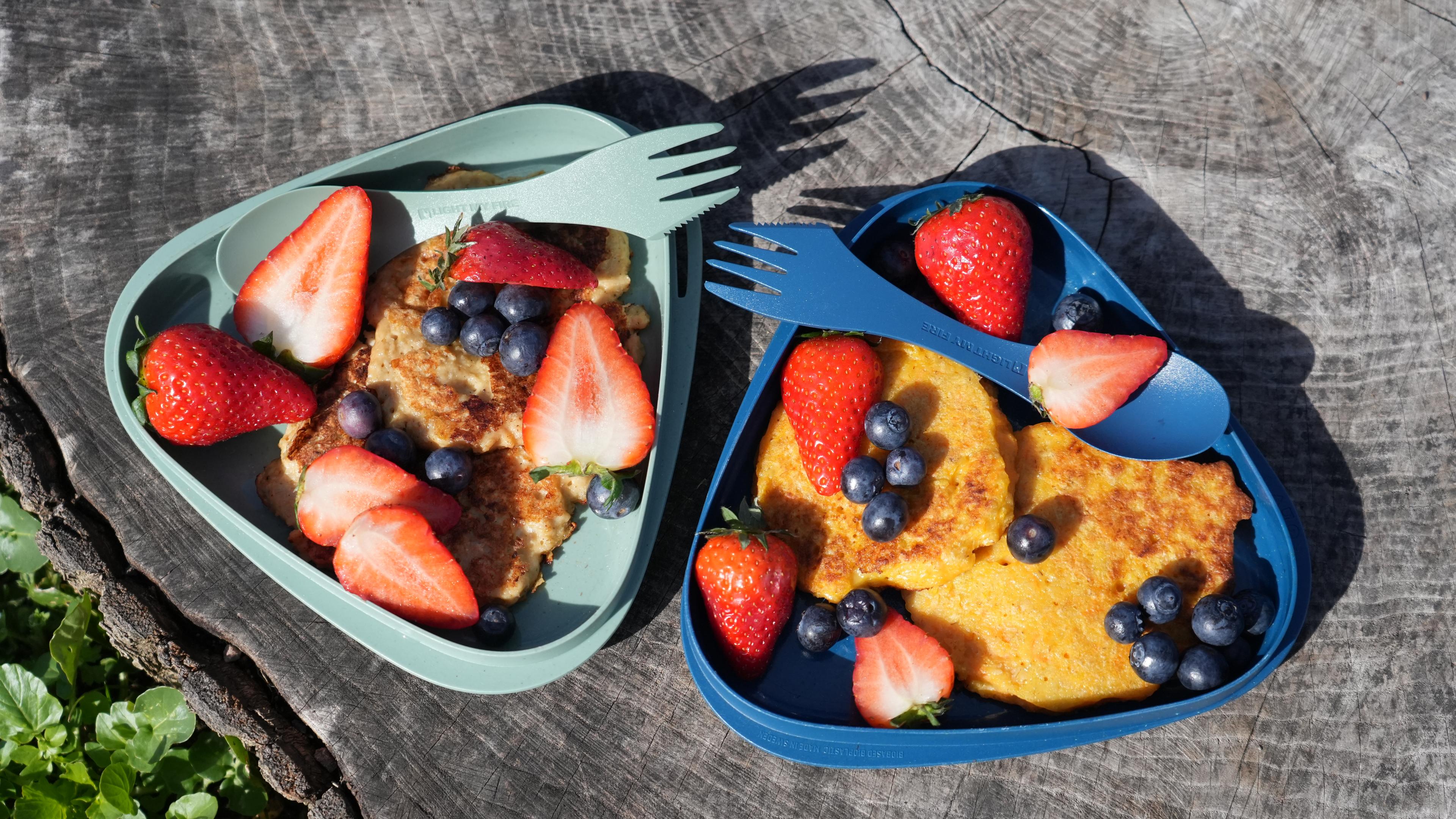 there are two plates of food with strawberries and blueberries on them .