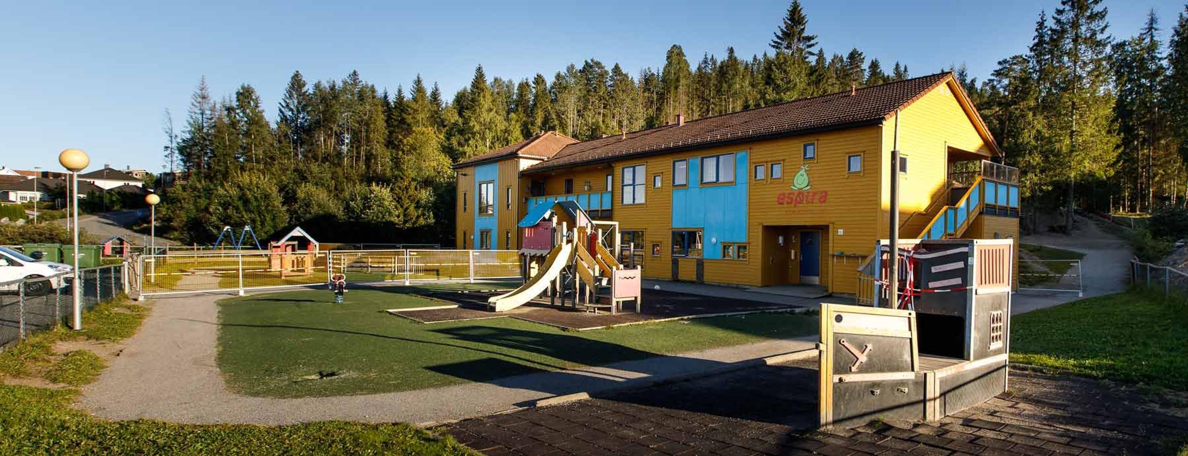 Espira Brådalsfjellet barnehage i Gjerdrum kommune med moderne bygg og lekestativer ute, omgitt av grønne områder som inviterer til aktiv lek og utforsking