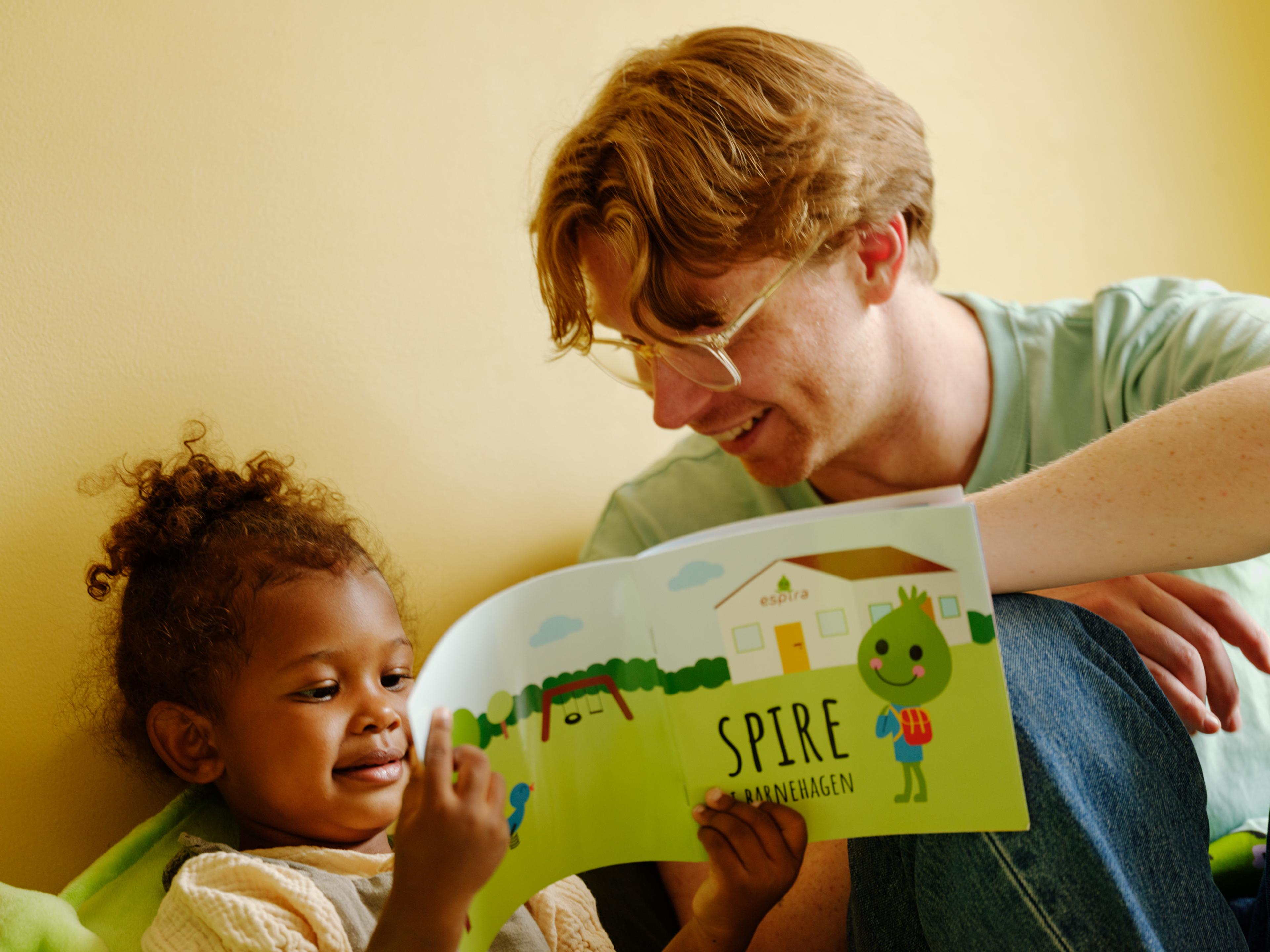 a man is reading a book to a little girl .