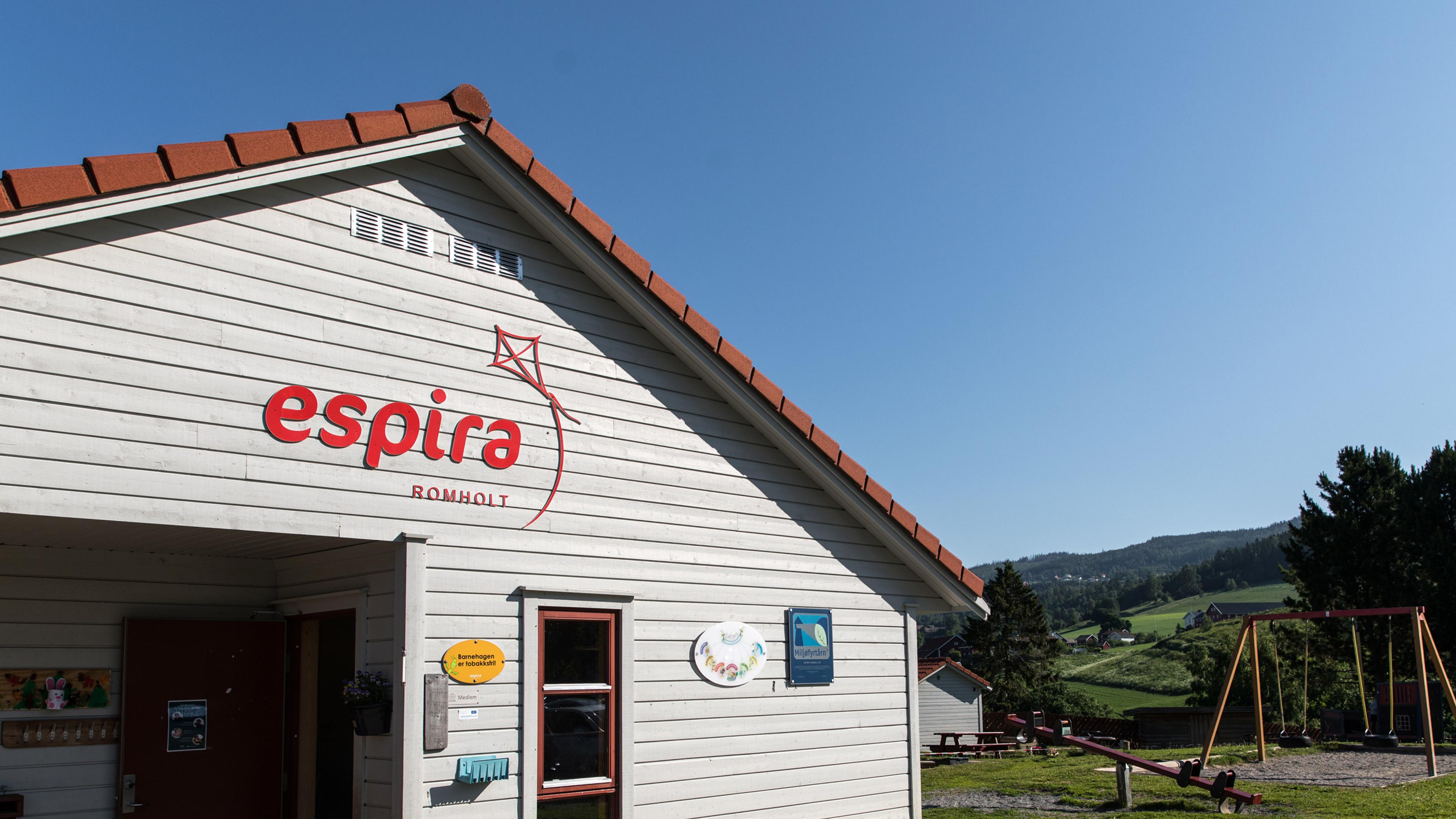 Espira Romholt barnehage i Søre Ålsbygda med lekeapparater og trær rundt uteområdet, et grønt og stimulerende miljø for lek, bevegelse og naturopplevelser