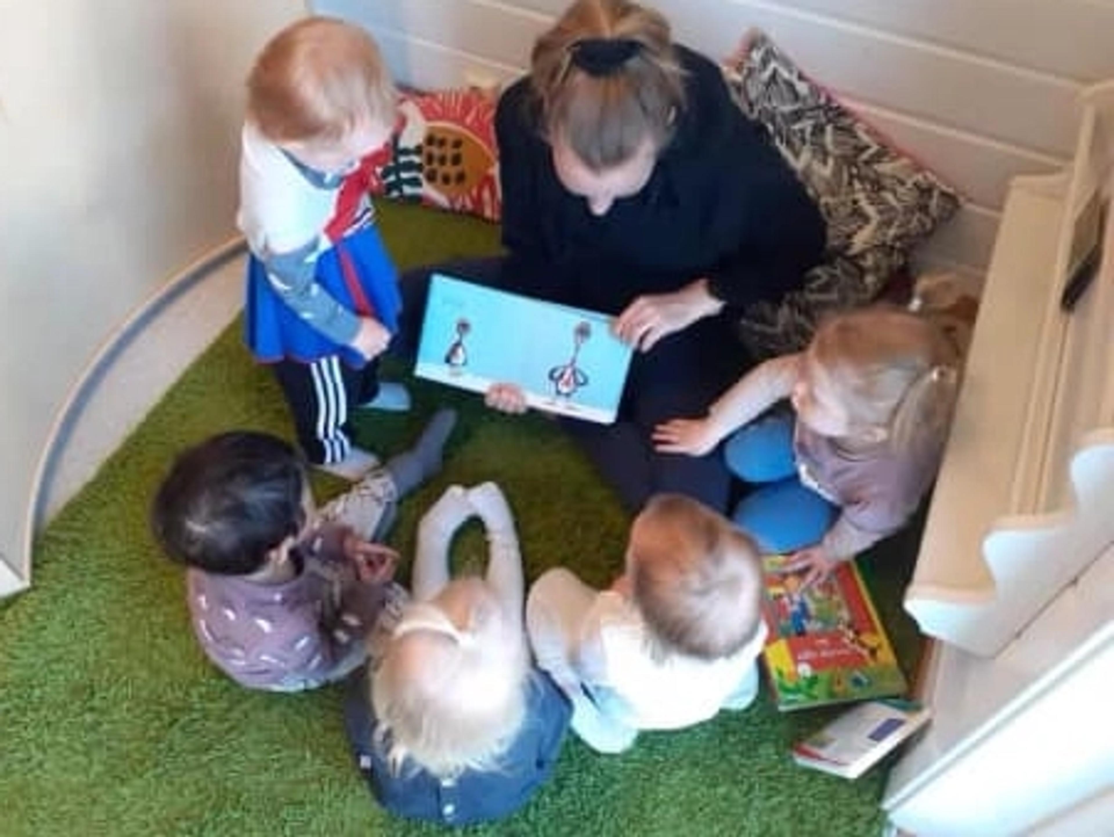 Ansatt som leser bok med barn