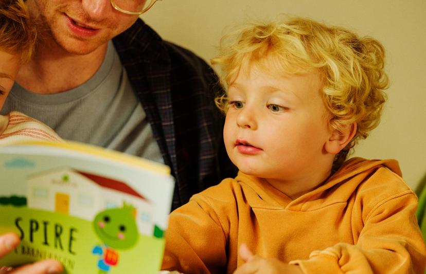 Mann leser høyt for to barn