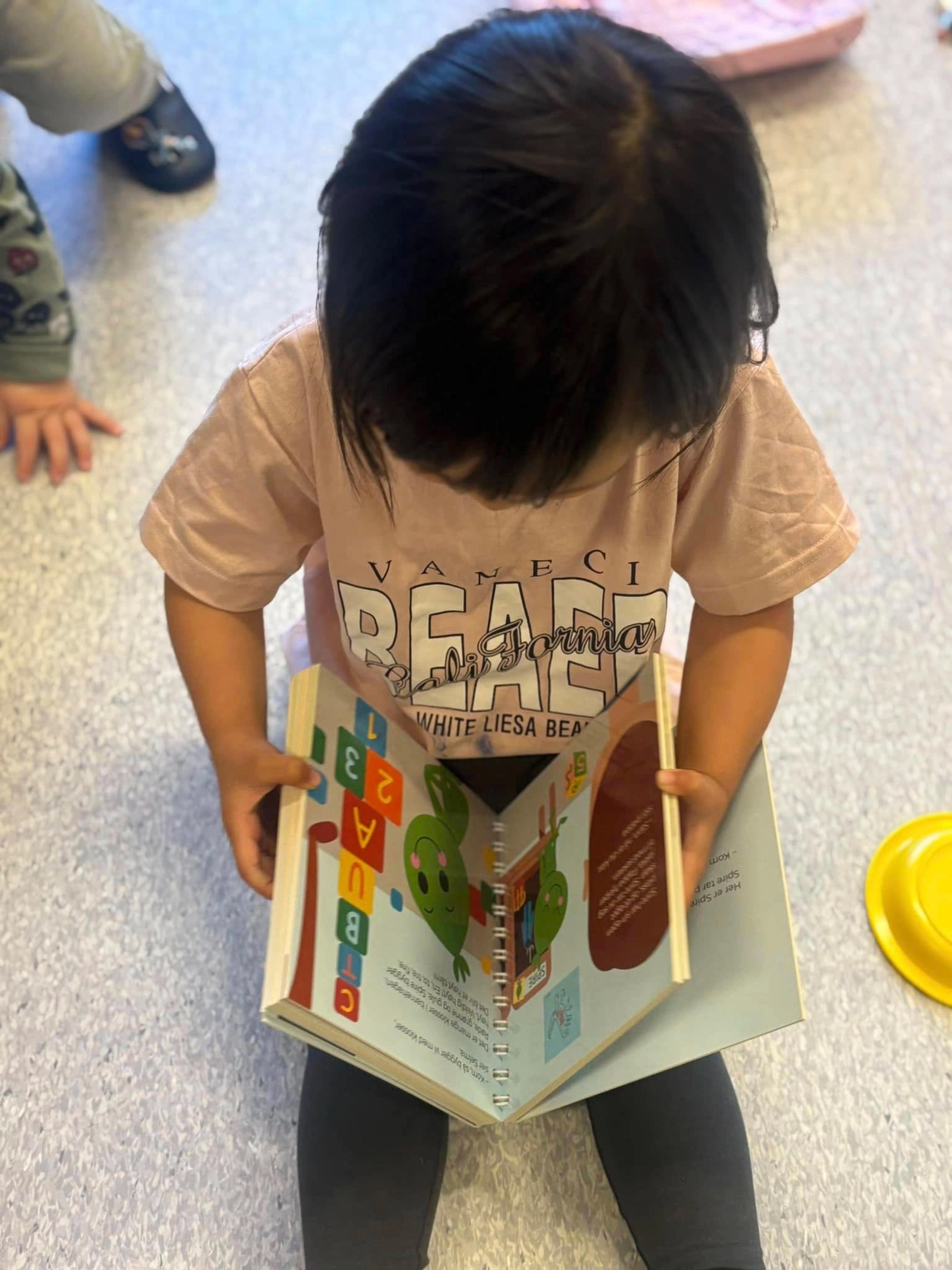 Barn som leser bok i Espira Myraskogen