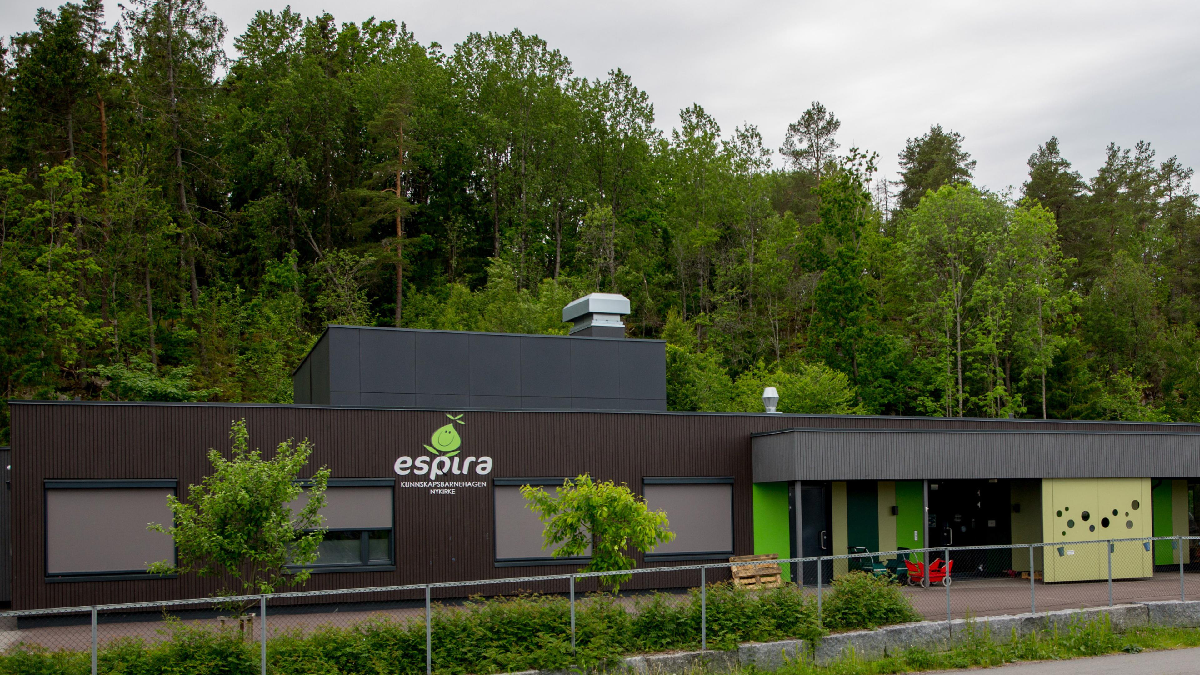 Fasaden på Espira Nykirke - brunt bygg med Espira-logo og skog i bakgrunnen