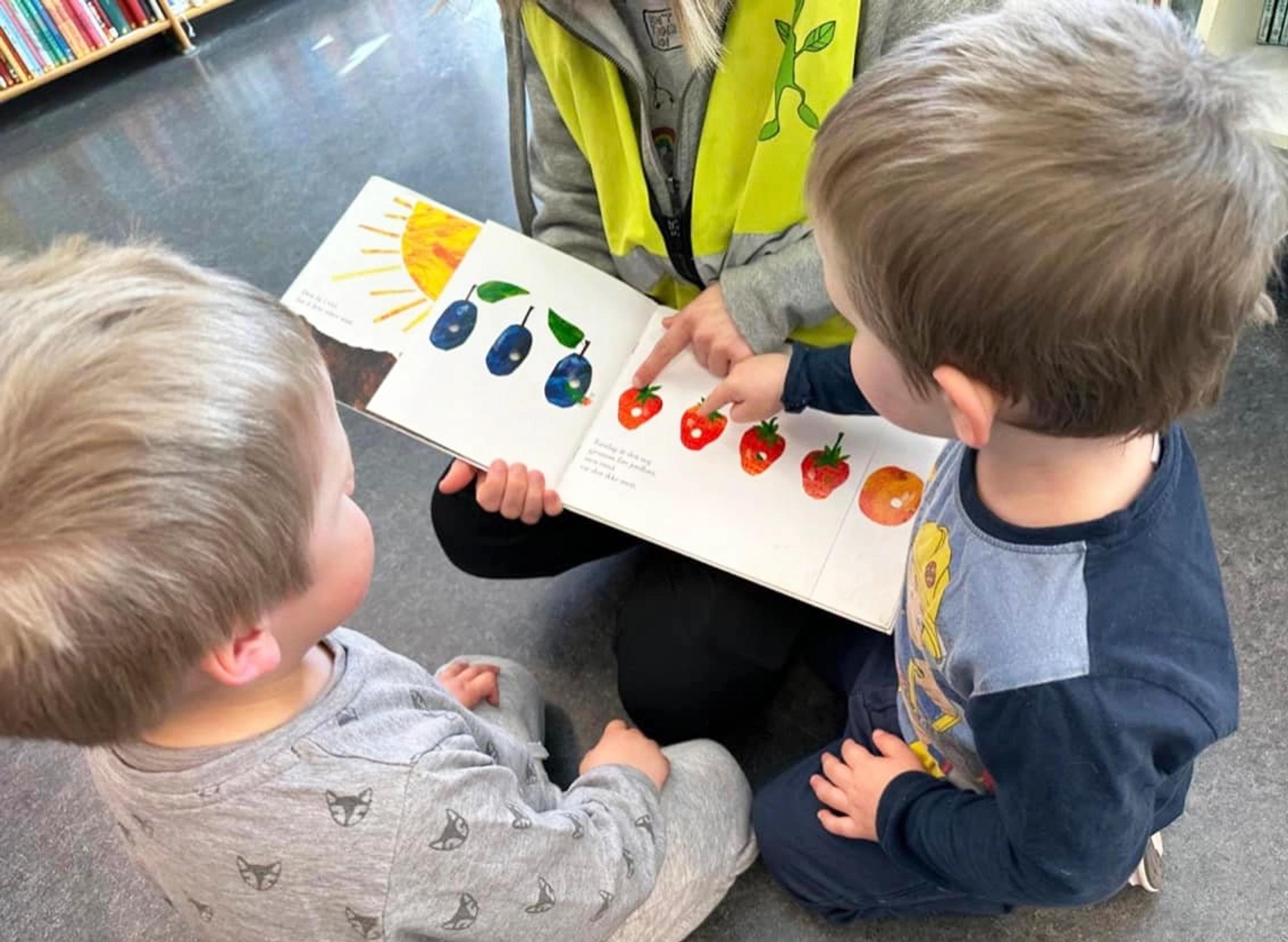 Barn som leser bok sammen med ansatt i Espira Solknatten
