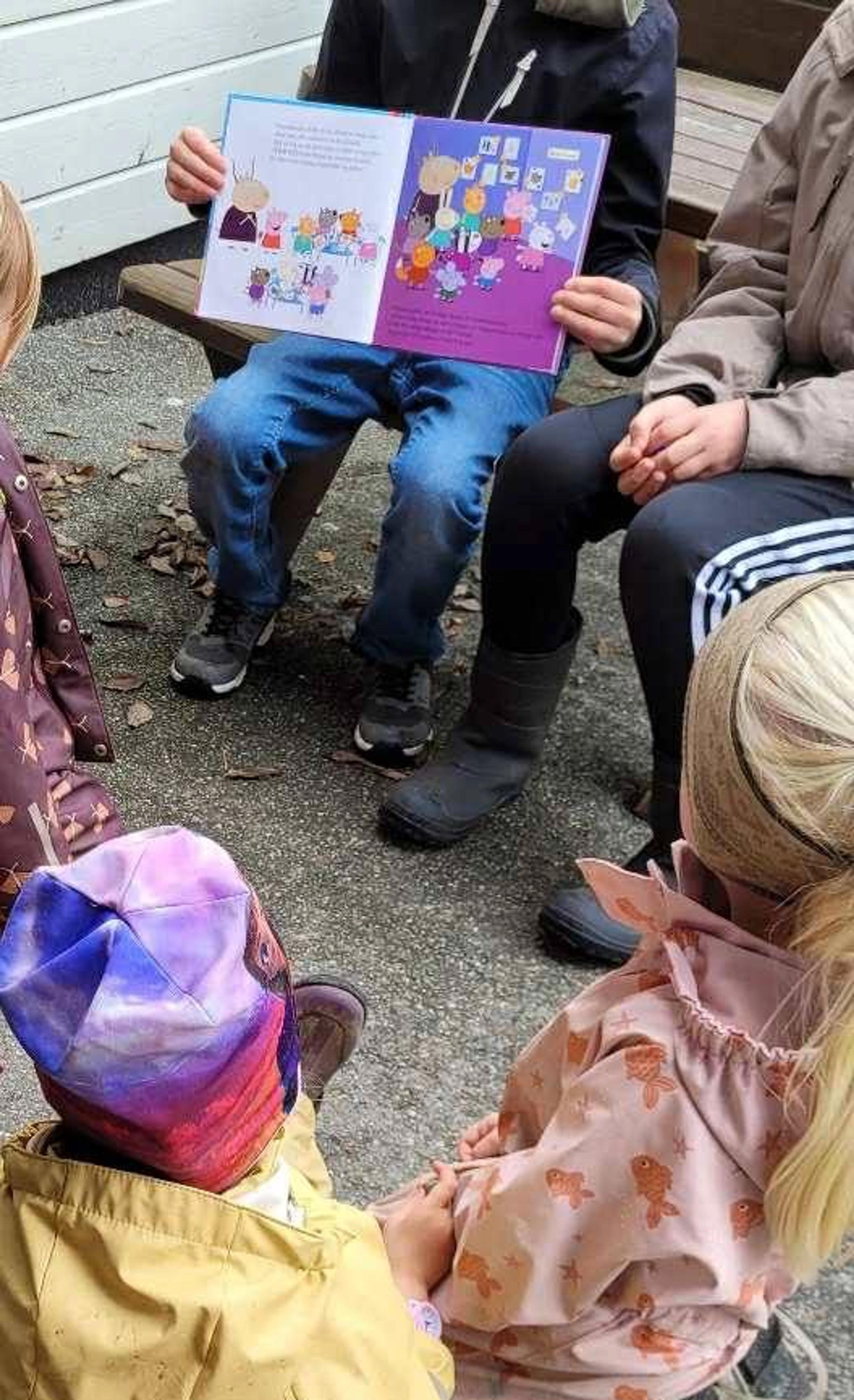 Ansatt som leser bok for barna i Espira Garhaug barnehage