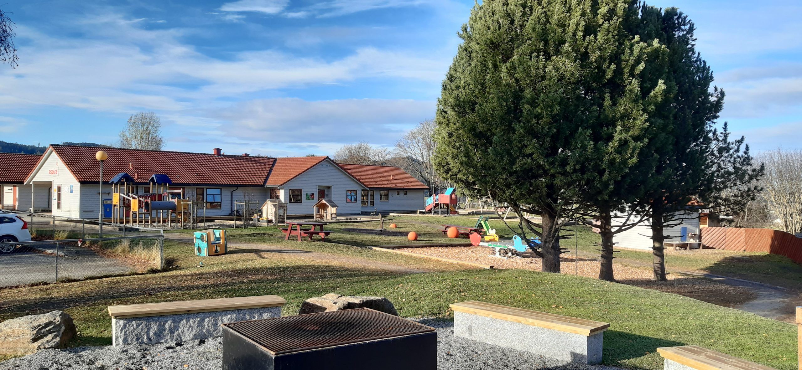 Espira Romholt barnehage i Søre Ålsbygda med lekeapparater og trær rundt uteområdet, et grønt og stimulerende miljø for lek, bevegelse og naturopplevelser