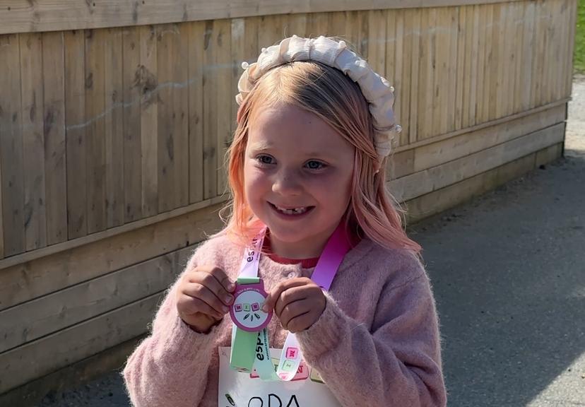 two little girls are running with one wearing a black sweatshirt that says skolespira 2022