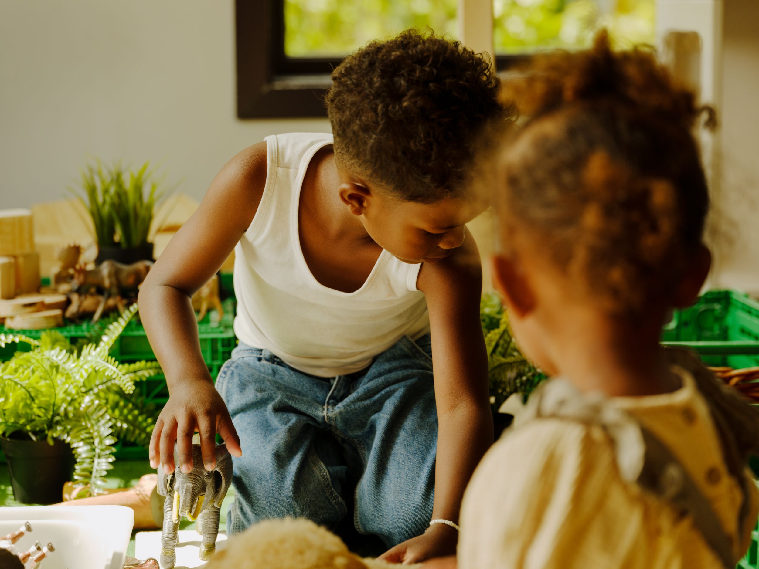 a boy and a girl are playing with toys in a kitchen .