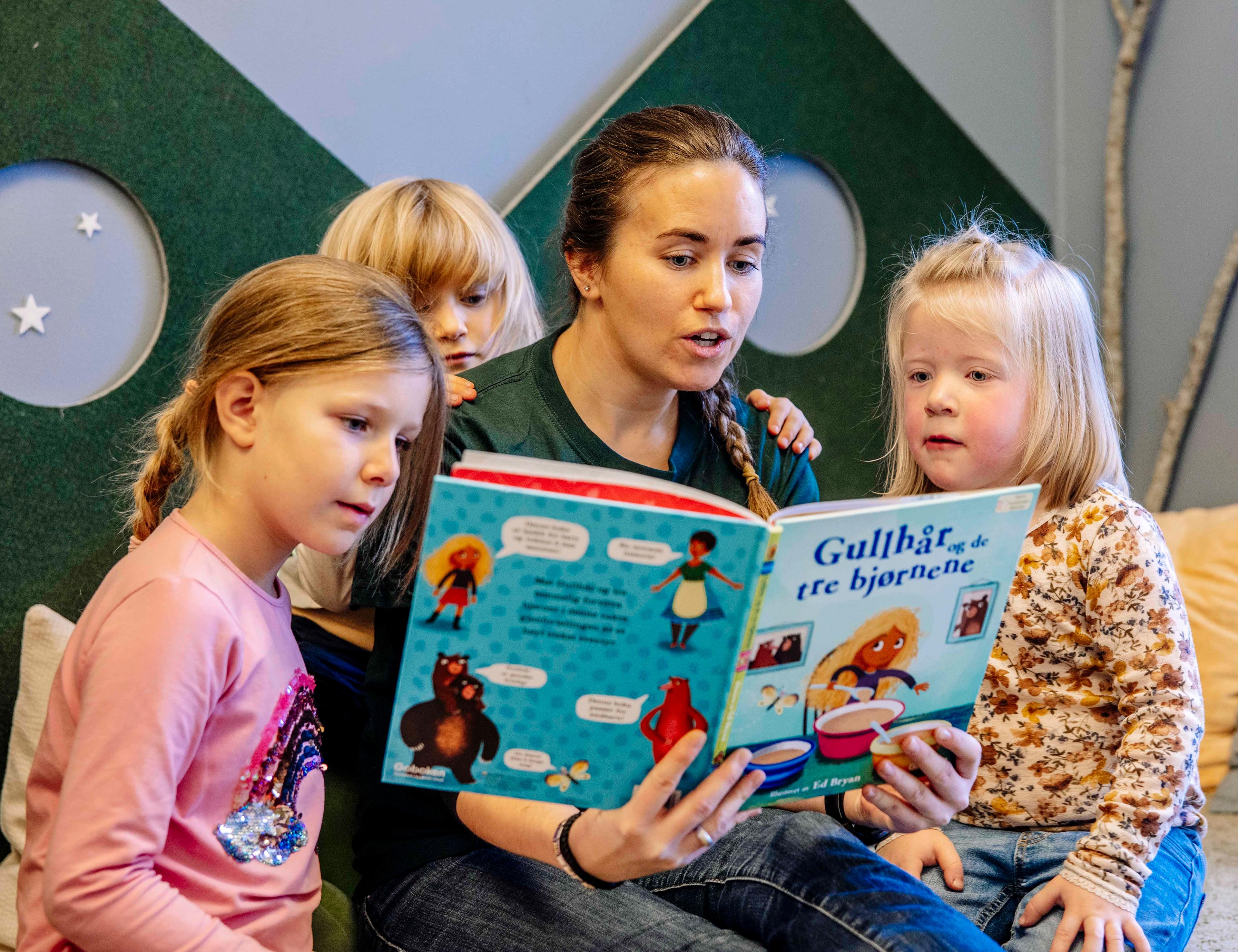 Ansatt som leser bok med barn (illustrasjonsbilde)