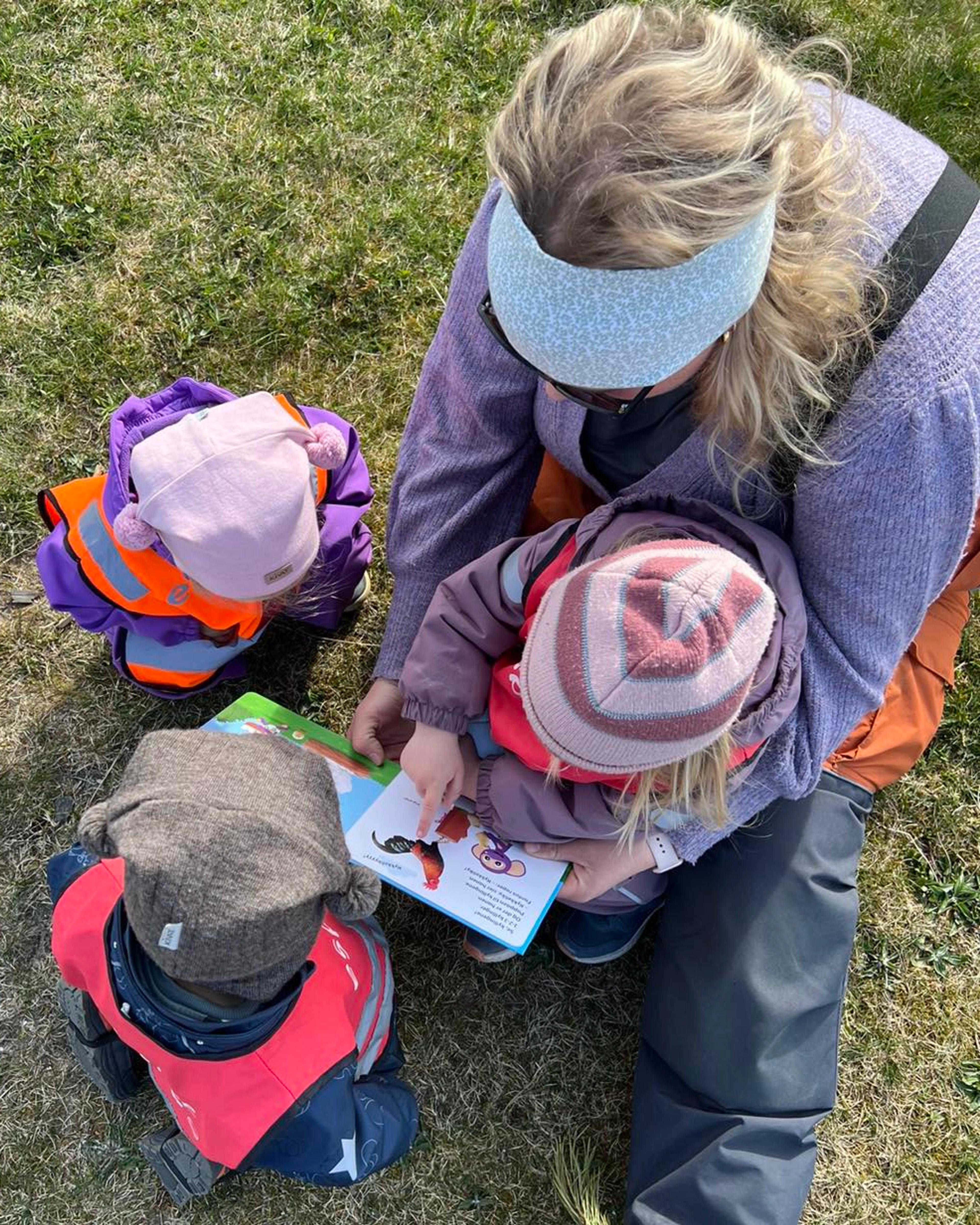 Ansatt som leser bok med barn i Espira Husebyparken