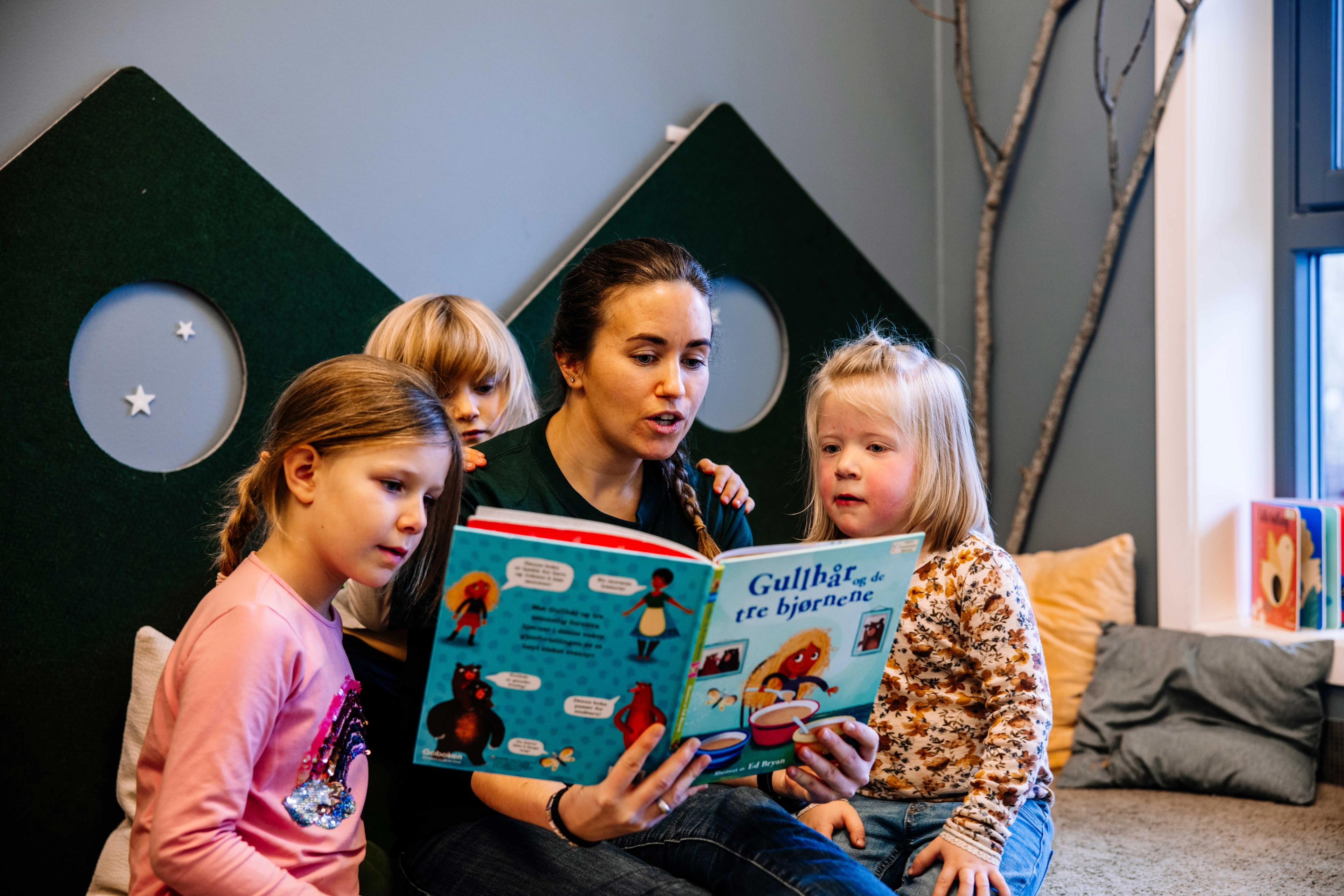 Ansatt i barnehagen leser bok sammen med barn. Lesestund