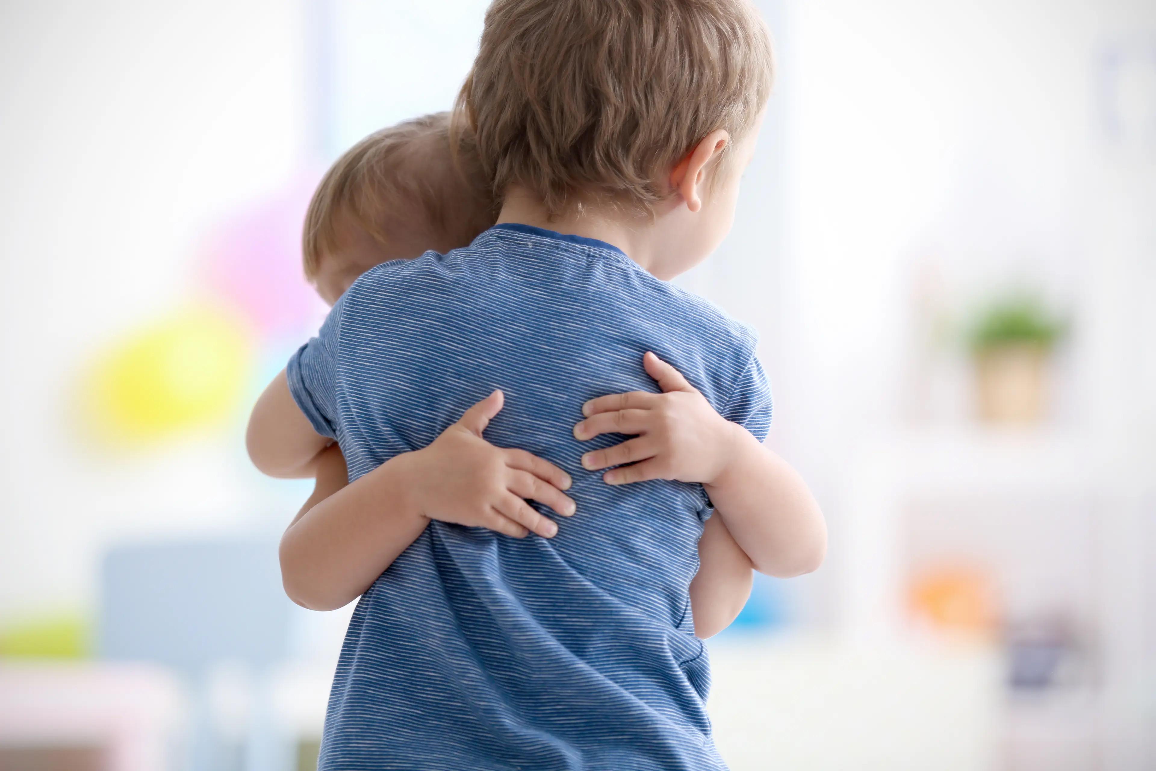 two young boys are hugging each other in a room .