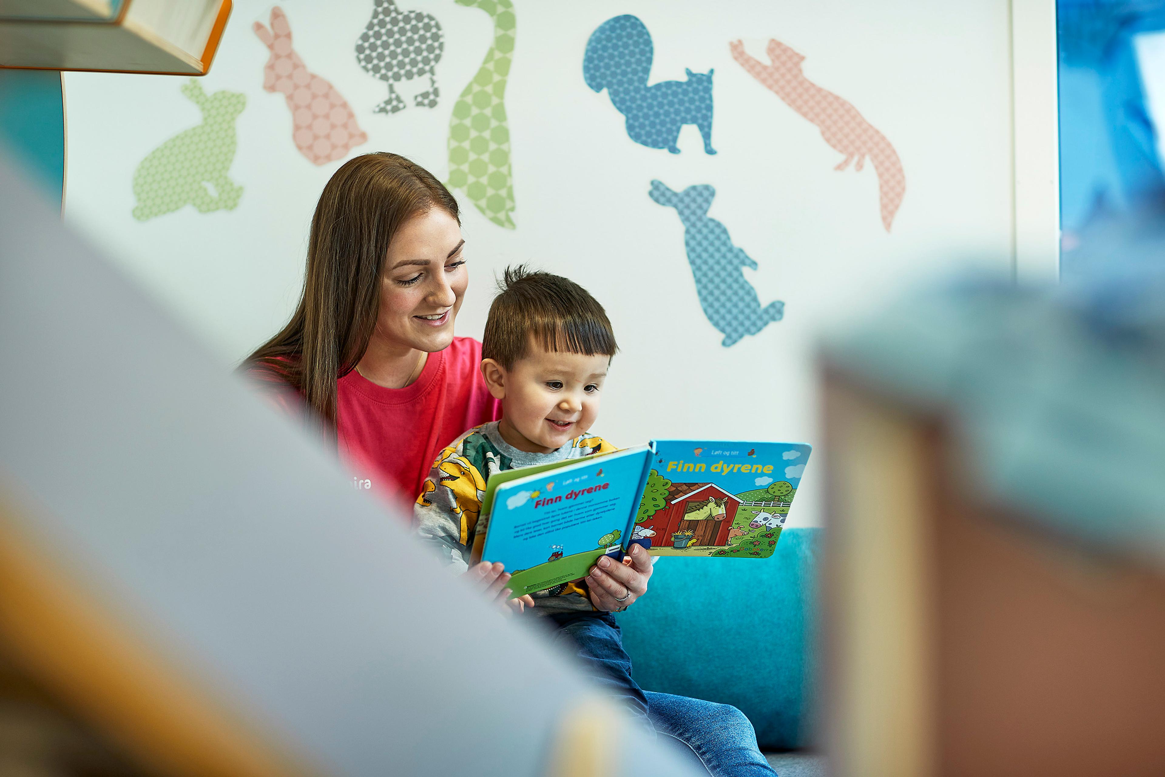 a woman is reading a book to a young boy .
