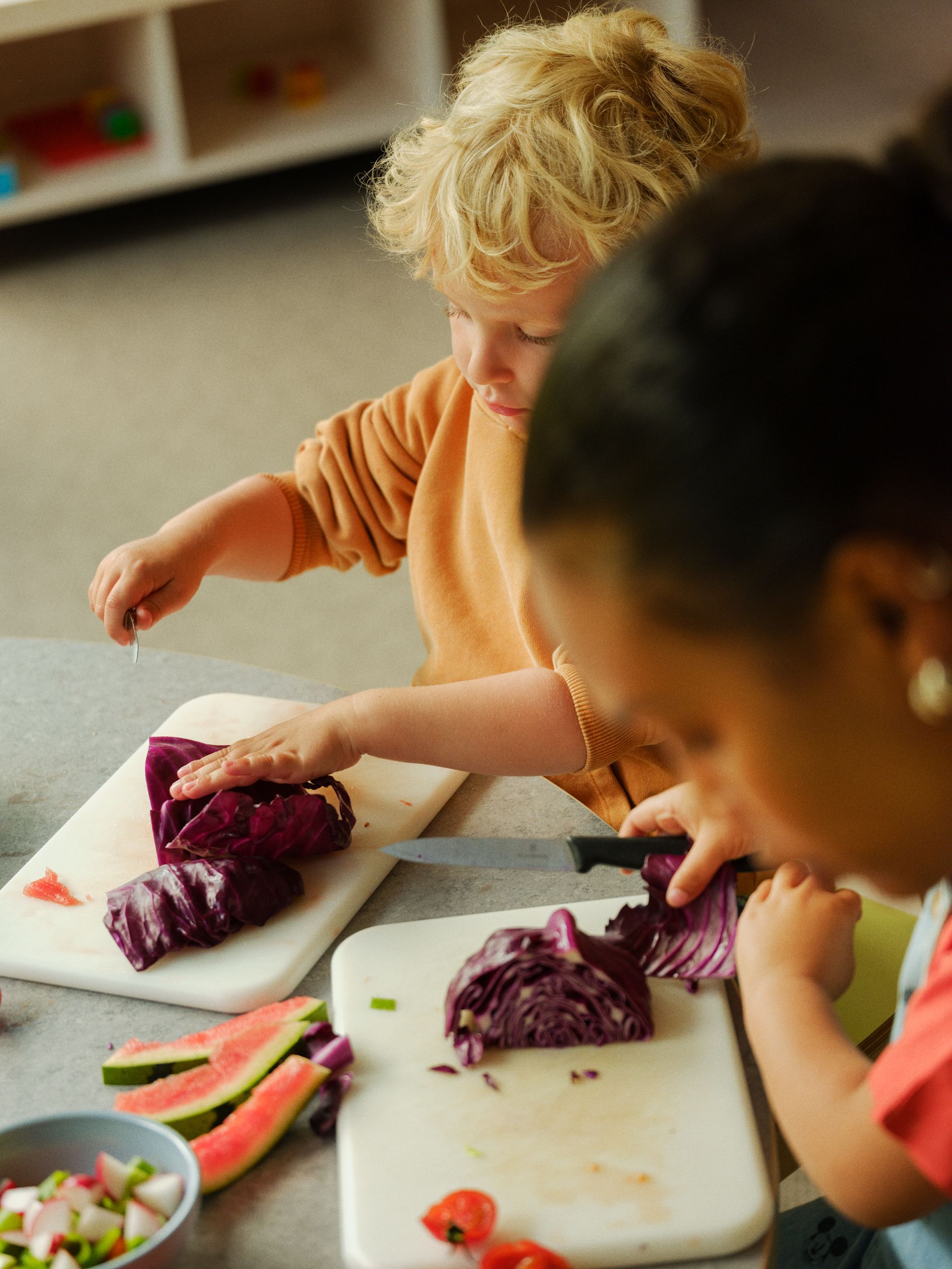 en gruppe med barn som kutter grønnsaker på et kuttebrett