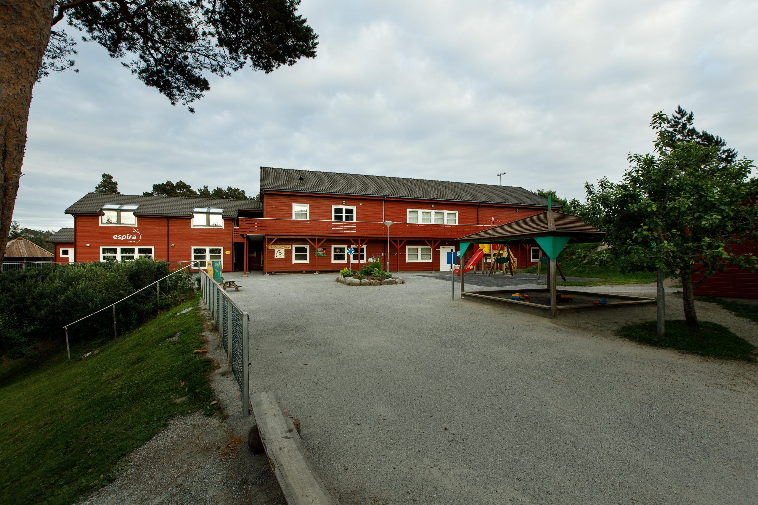 Rødt barnehagebygg hos Espira Finnås på Bømlo – barnehage i naturskjønne omgivelser med trygt og innbydende uteområde