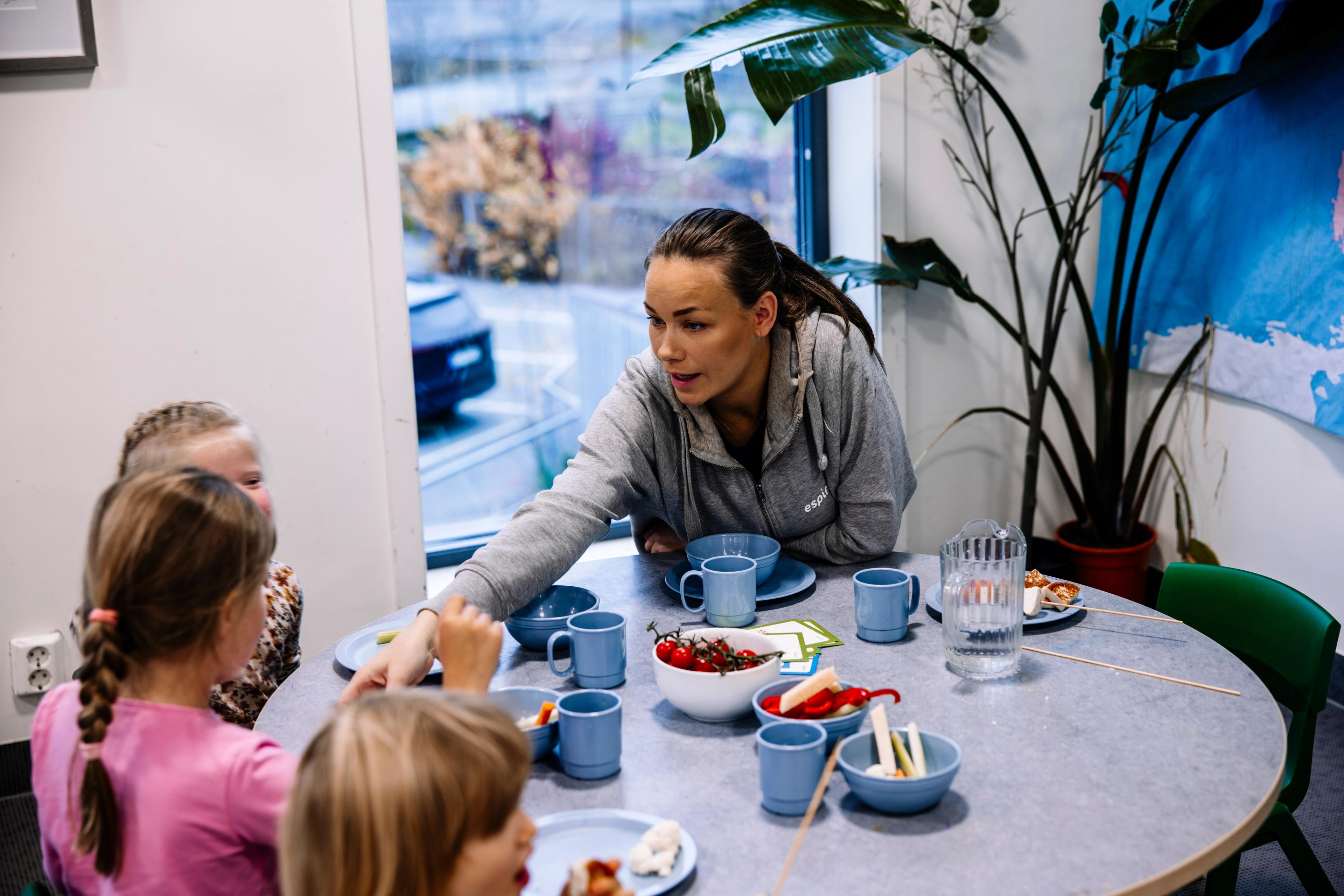 Ansatt i Espira barnehage som har et sosialt og sunt måltid sammen med barna