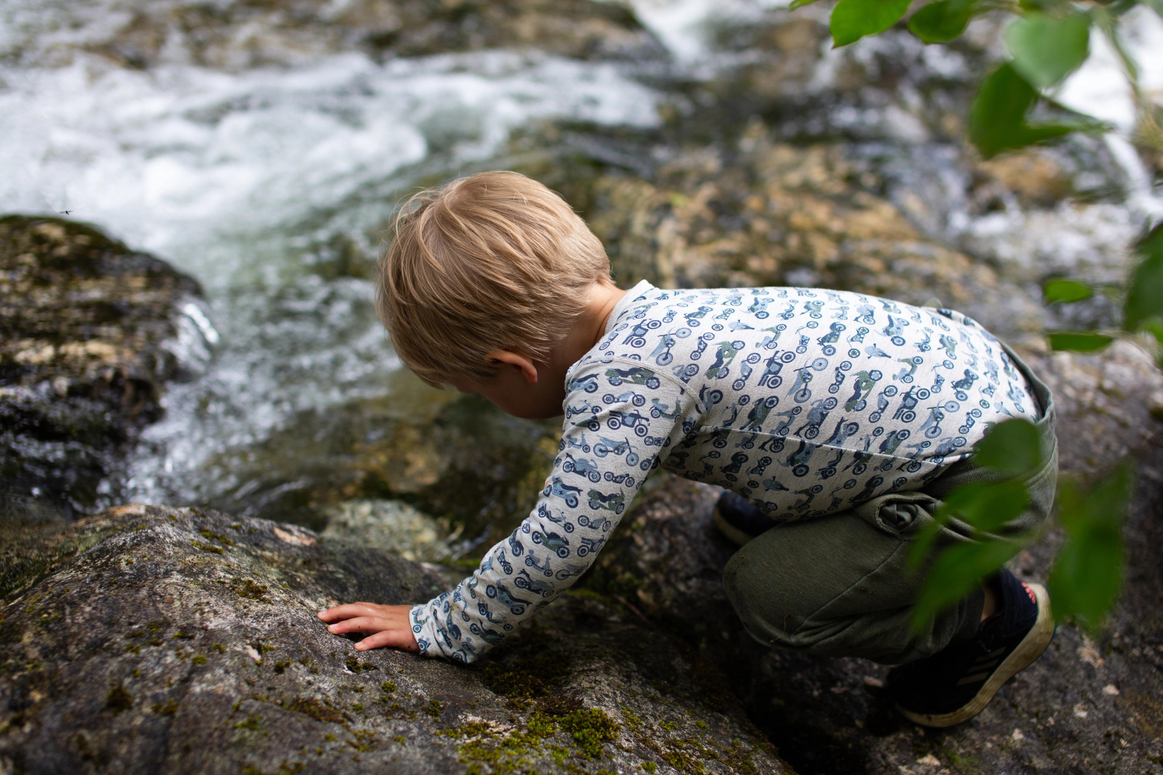 Barn som utforsker en elv. Vannlek.