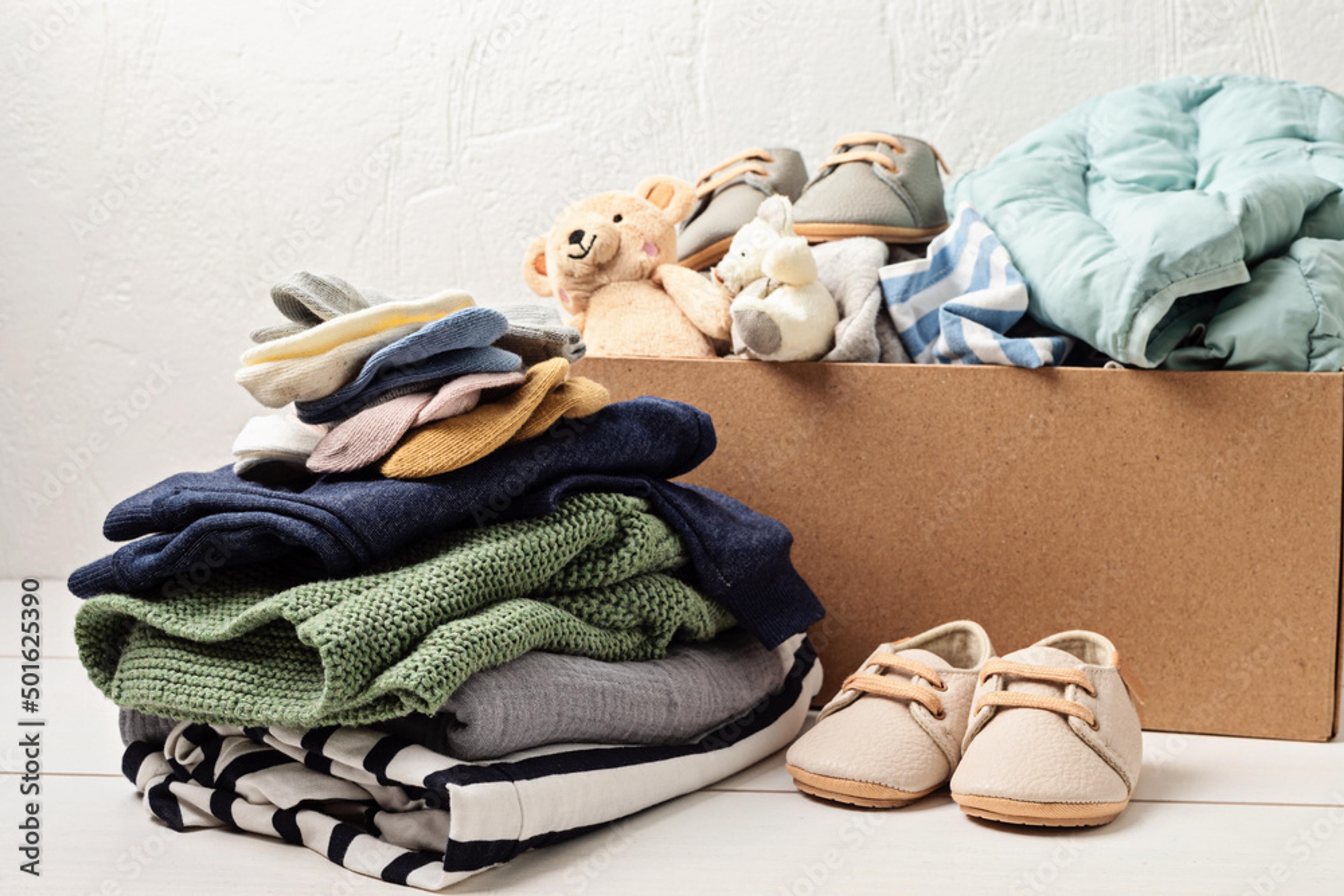 a cardboard box filled with baby clothes and shoes .