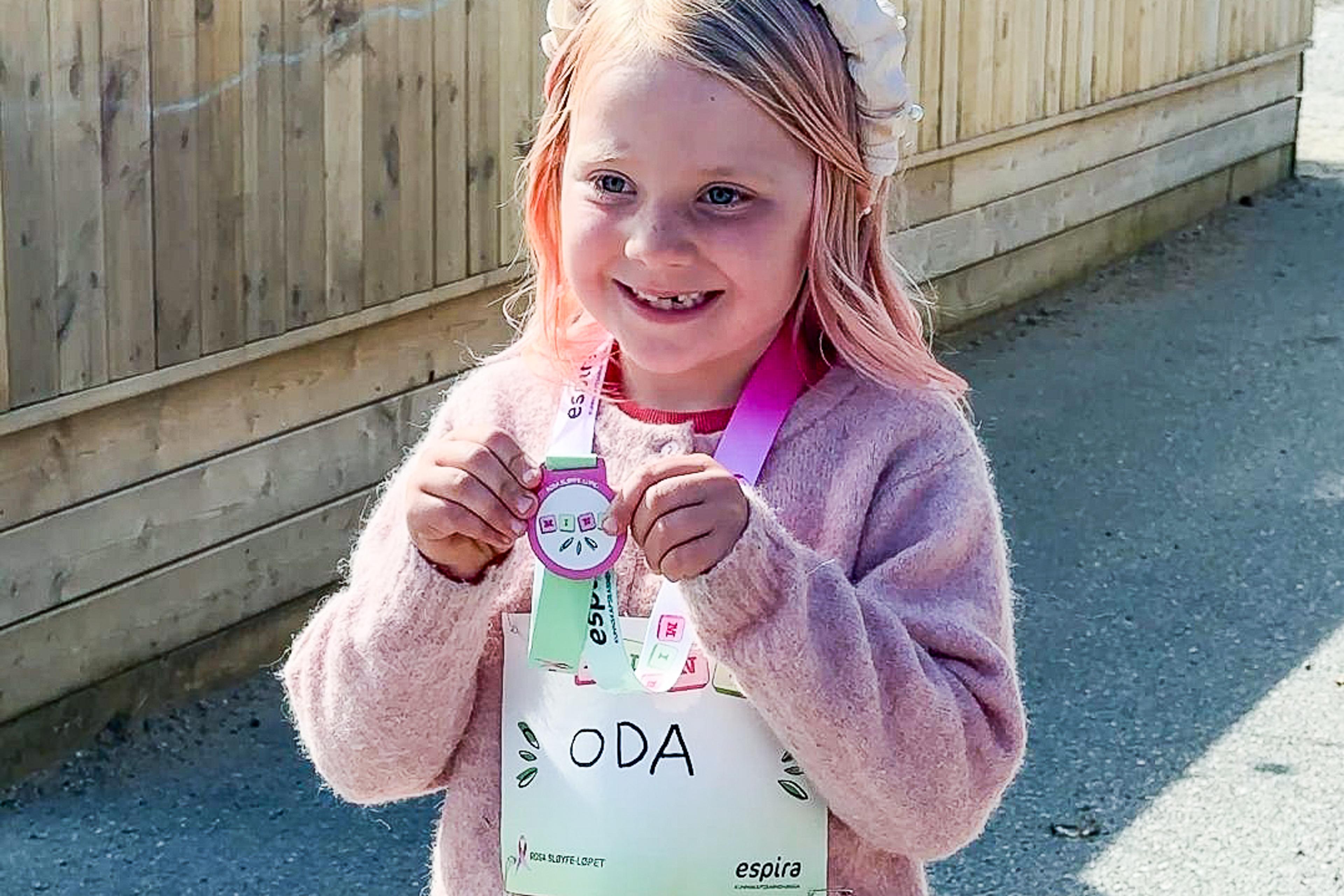 En glad jente med medalje fra Rosa sløyfe-løpet.