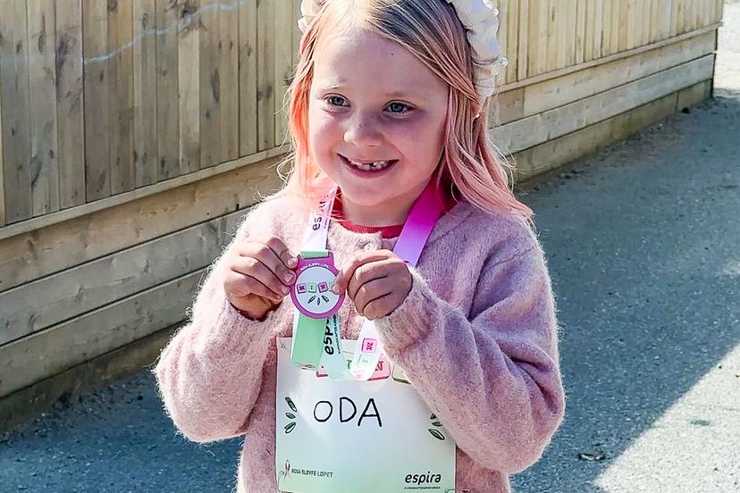 En glad jente med medalje fra Rosa sløyfe-løpet.