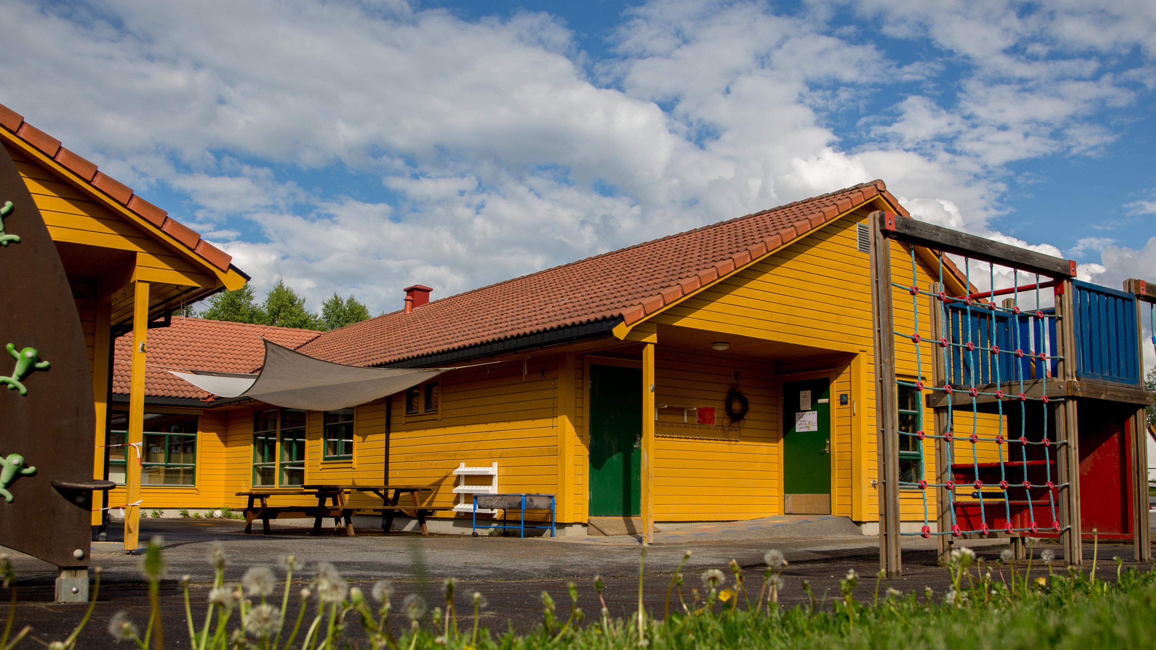 Espira Opaker barnehage i Oppaker, Nes kommune, med gult bygg sett utenfra og klatrestativ i forgrunnen, et trygt og stimulerende uteområde for lek, bevegelse og sosialt samspill