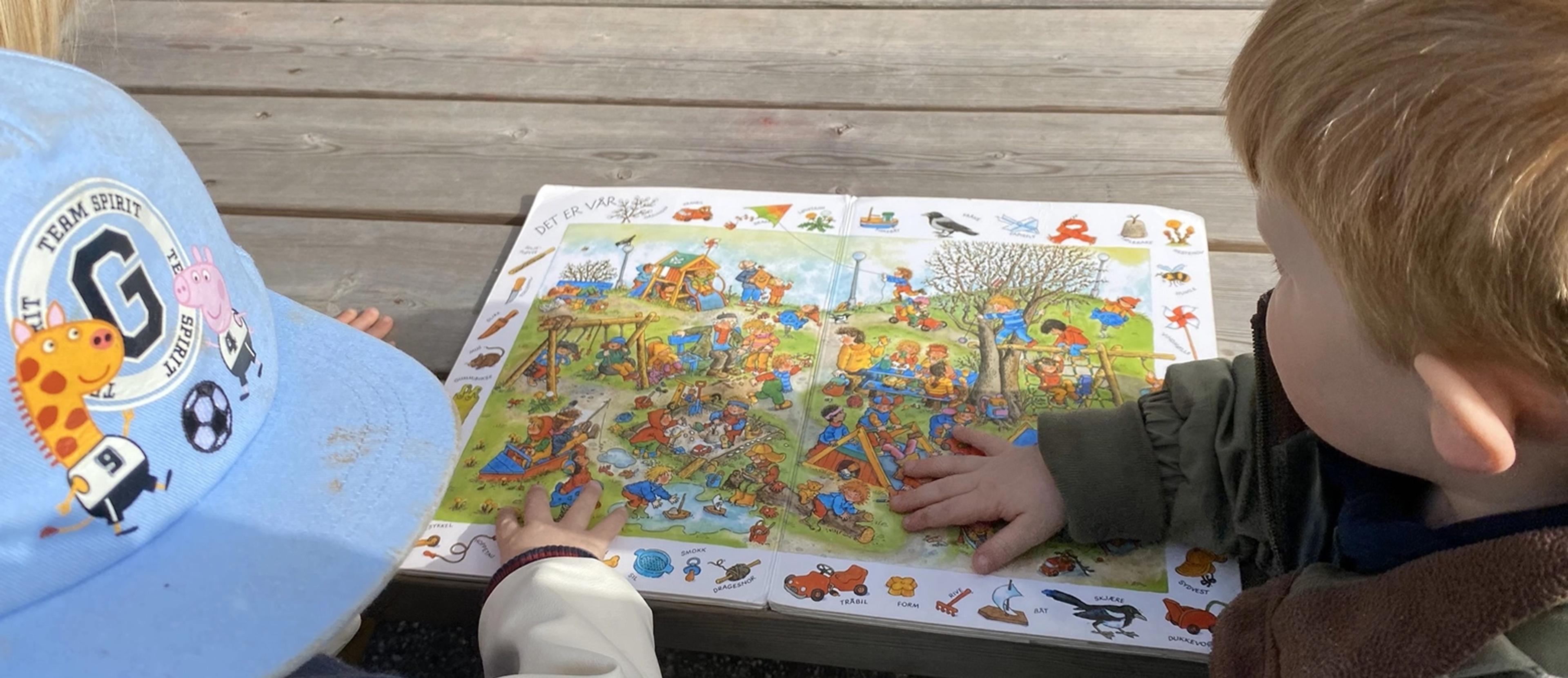 Barn som leser bok sammen ute i Espira Kløverenga
