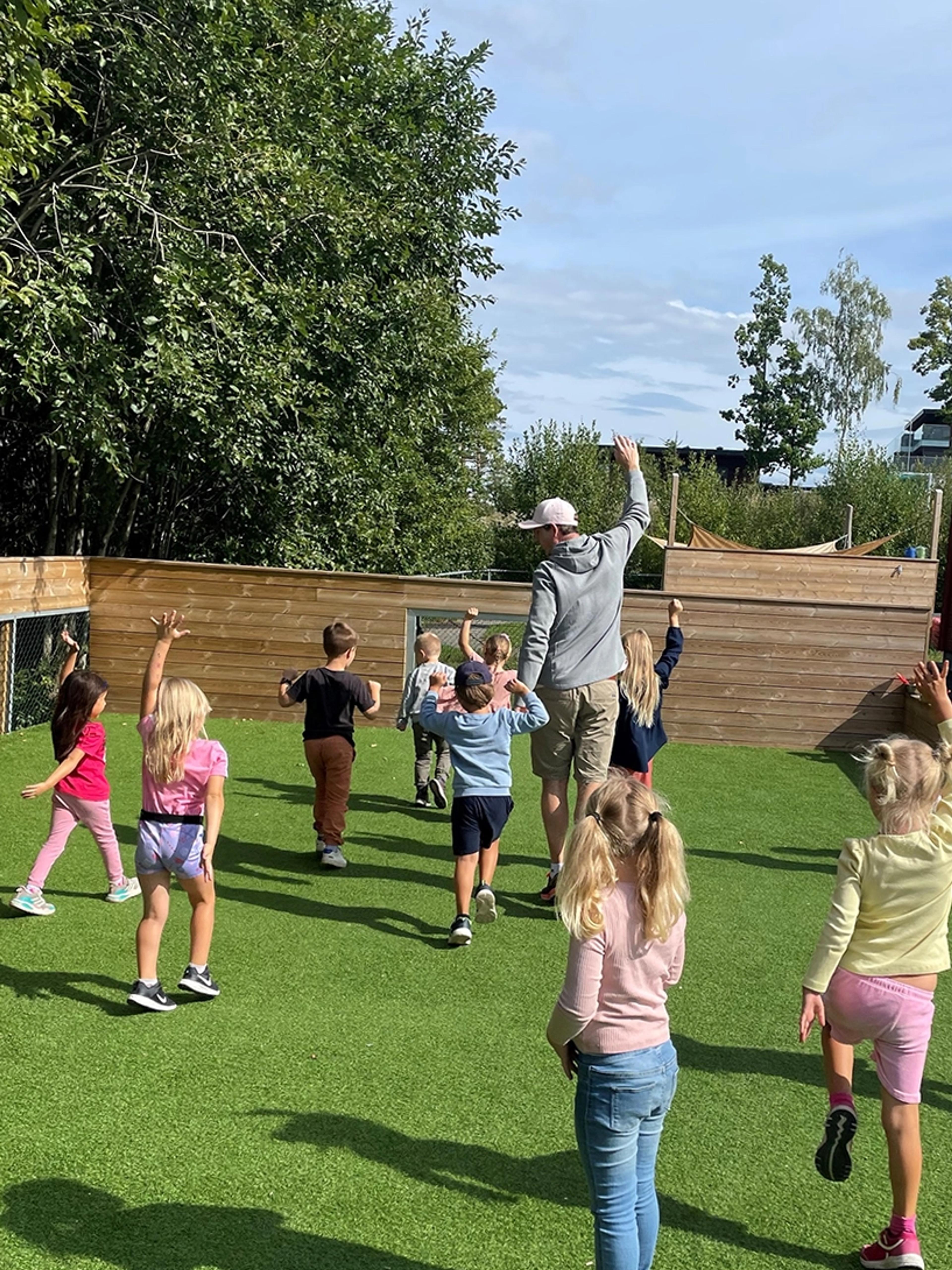 Barn og ansatt som danser sammen på Espira Kniveåsen sitt uteområde