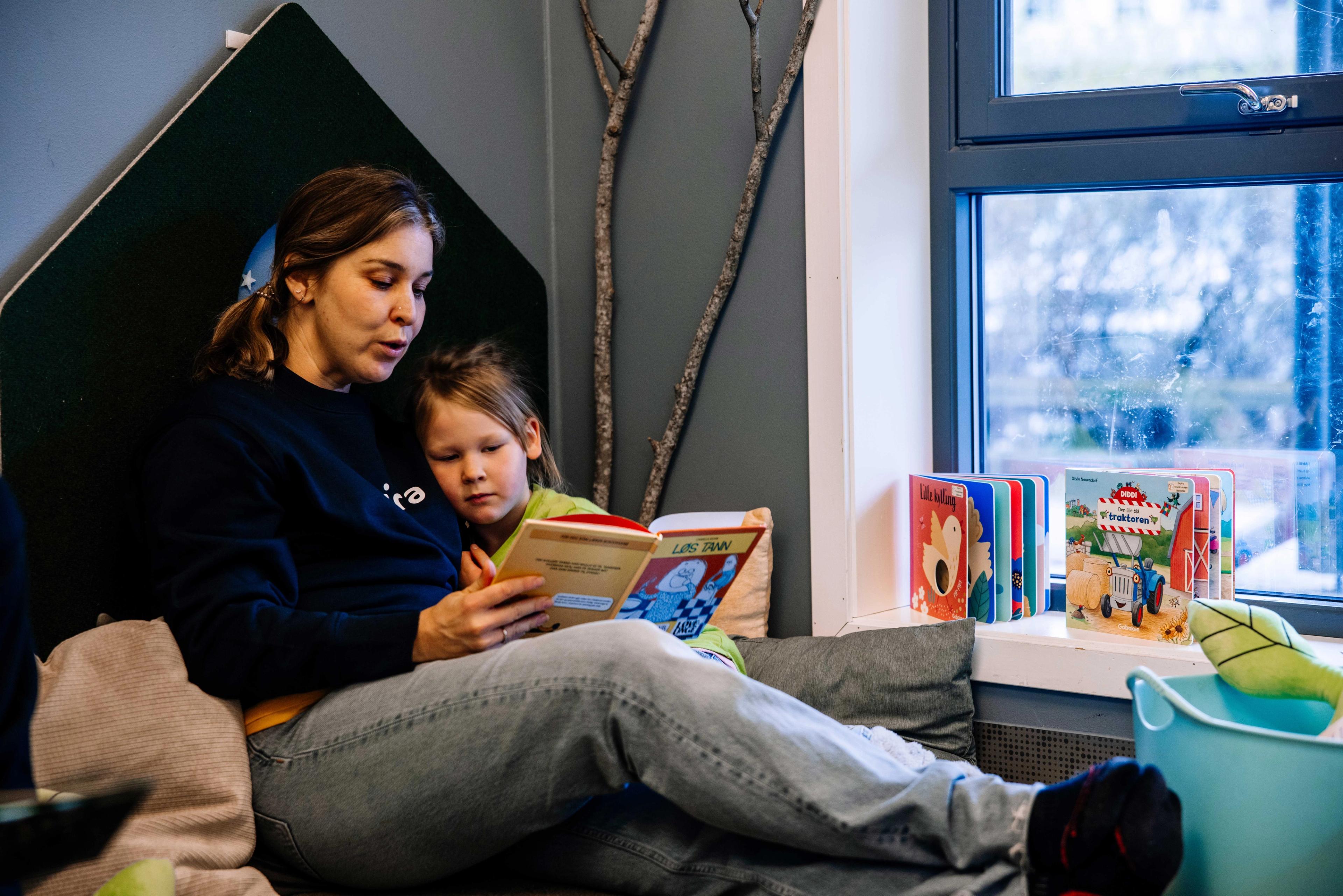Ansatt og barn som leser bok i Espira