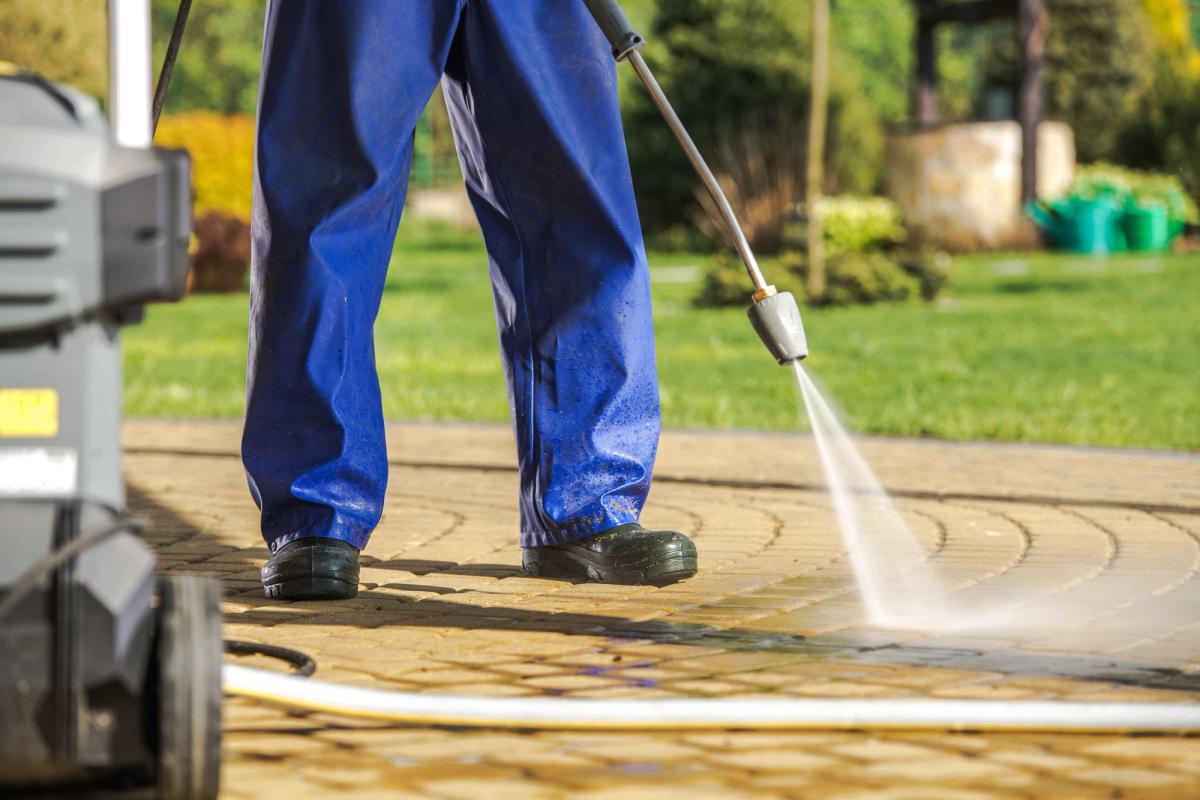 Worker pressure washing interlock paver patio, Niagara