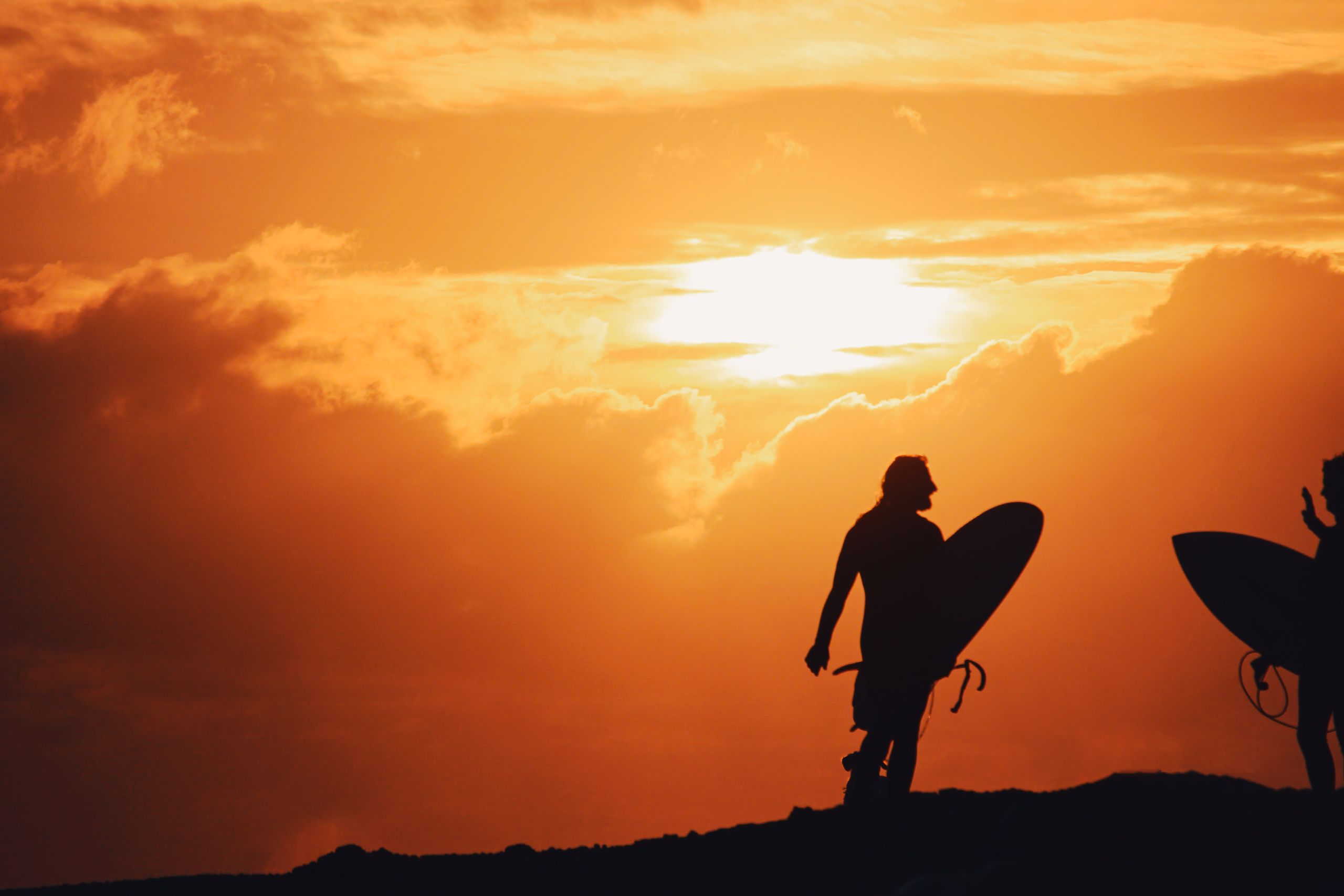 Silhouette of a surfer walking with a board at sunset — the beginning of the Sea Me Smile story